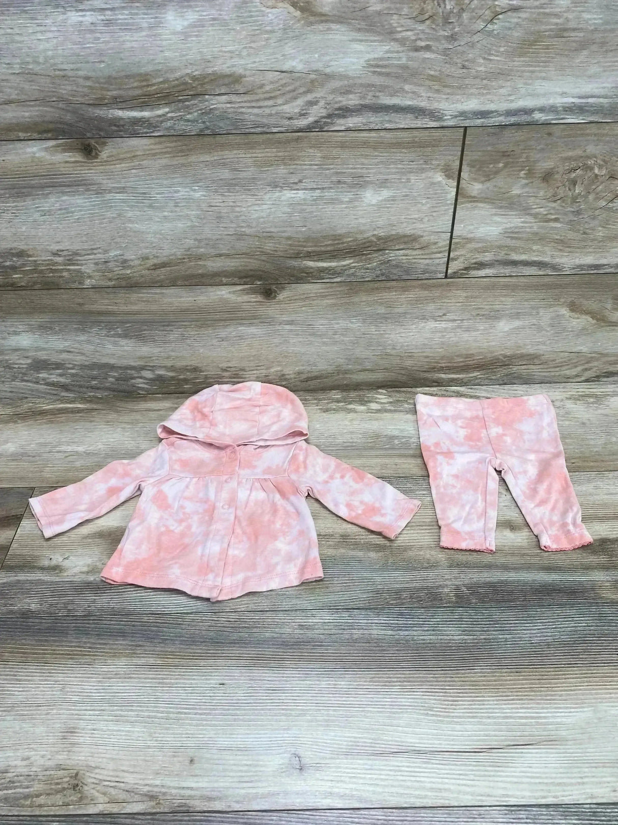 Flat lay of Carter’s pink two-piece hooded top and leggings showing gathered-waist hooded top and matching leggings on wood floor