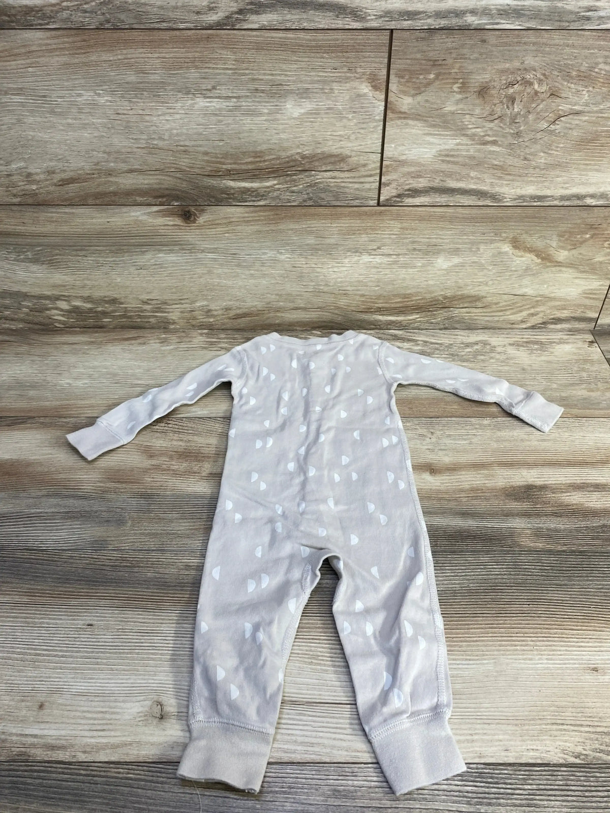 Flat lay Ivory Easy-Peasy footless sleeper 12m with long sleeves, cuffed ankles and white semicircle print on wood floor