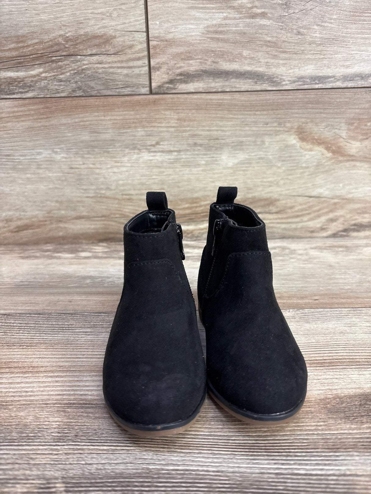 Front view of Cat & Jack Penelope boots in black suede size 7C showing side zippers and rubber soles on wood background