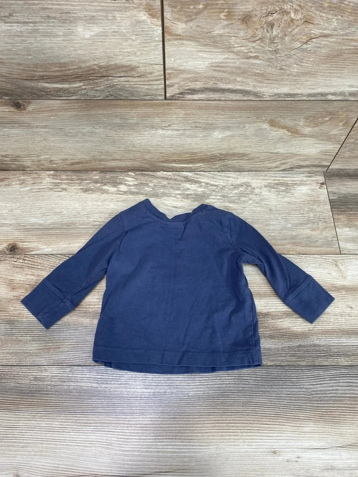 Back of Hanna Andersson navy long-sleeve organic baby shirt on wood floor