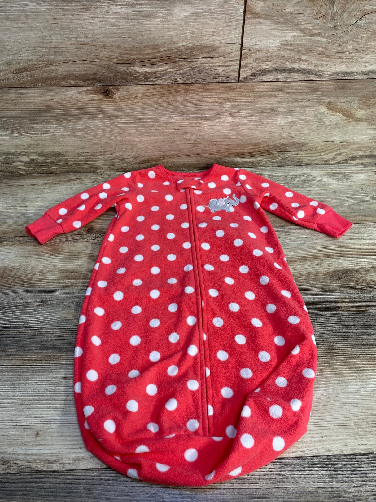 Red baby sleep sack with white polka dots and an embroidered elephant on wood floor