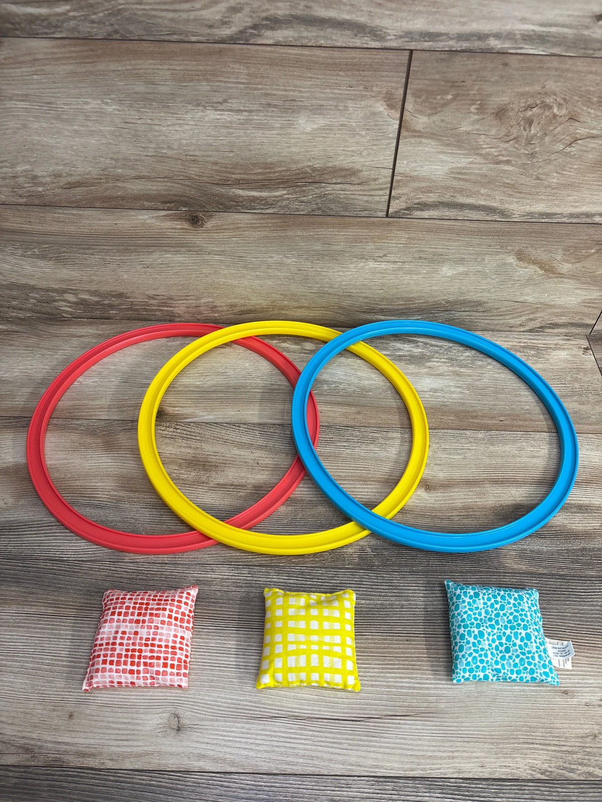 Red, yellow, and blue tossing rings with matching patterned bean bags on wood floor