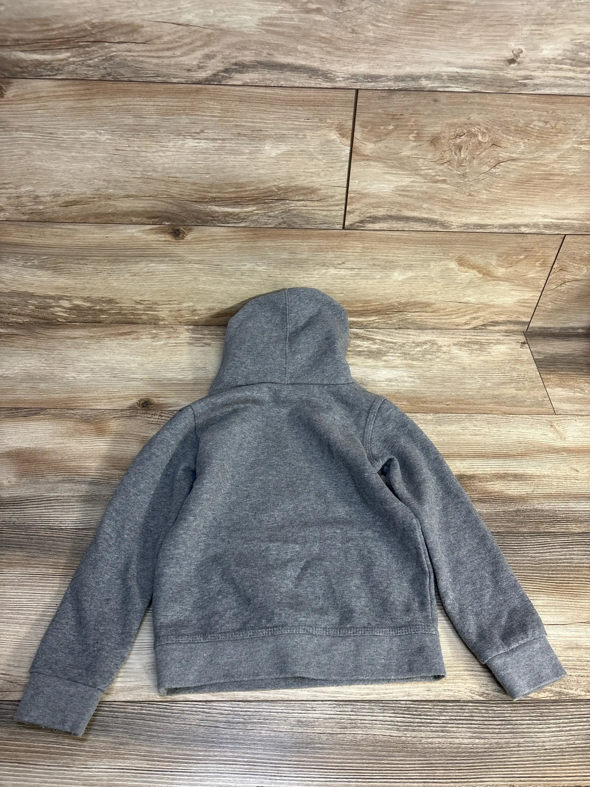 Gray kids hoodie laid flat on wood floor, cozy children's clothing for resale