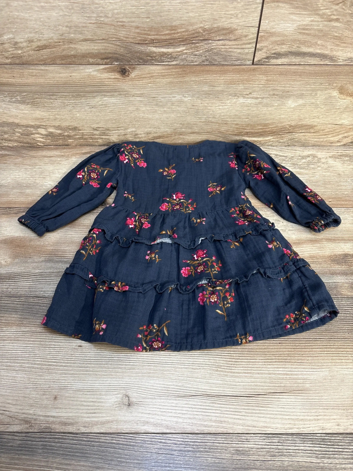 Girls long sleeve navy floral dress with ruffle skirt, laid flat on wood background