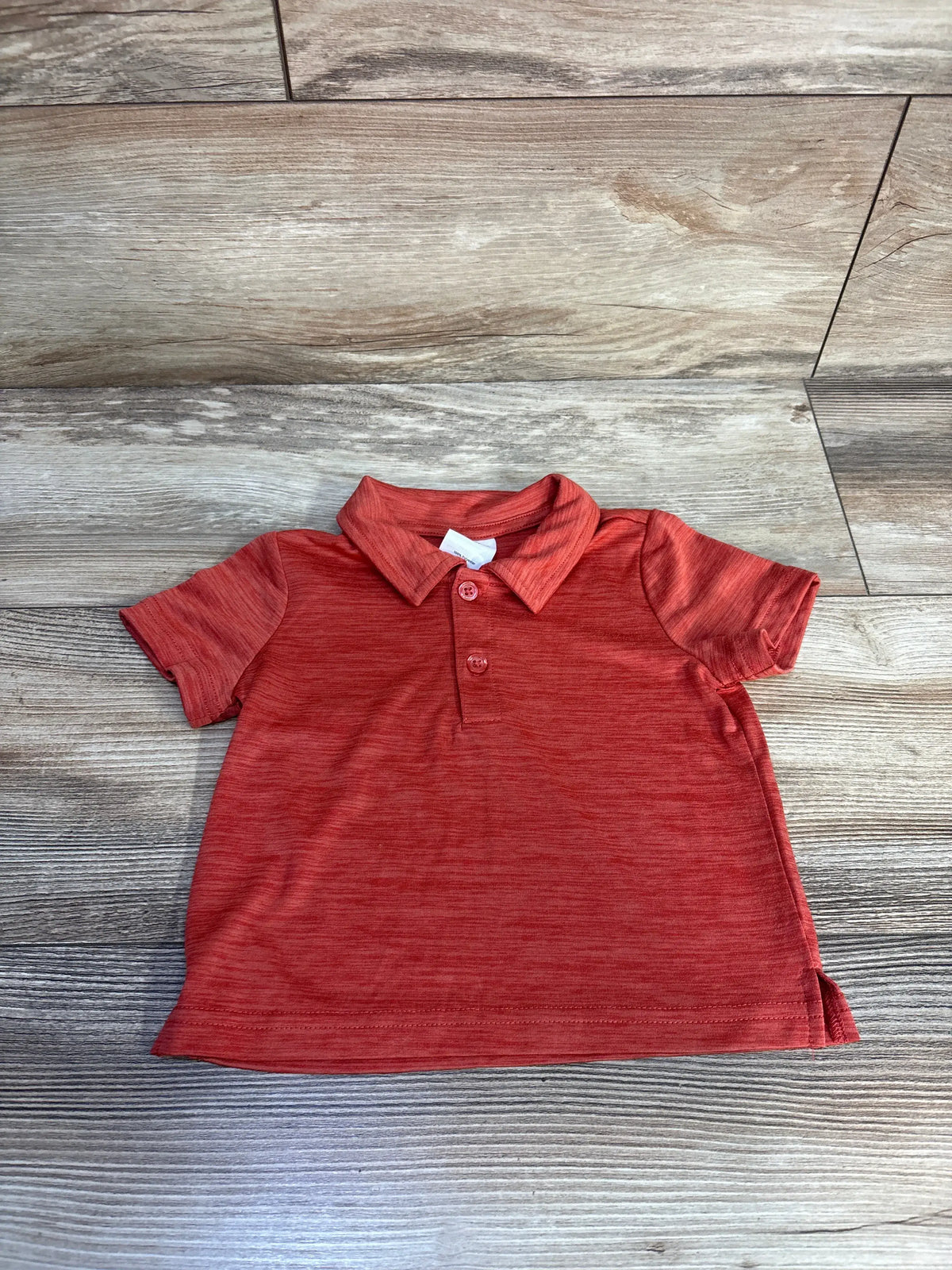 Front view of a red Okie Dokie active polo shirt in size 12 months showcasing collar and two-button placket on wood floor
