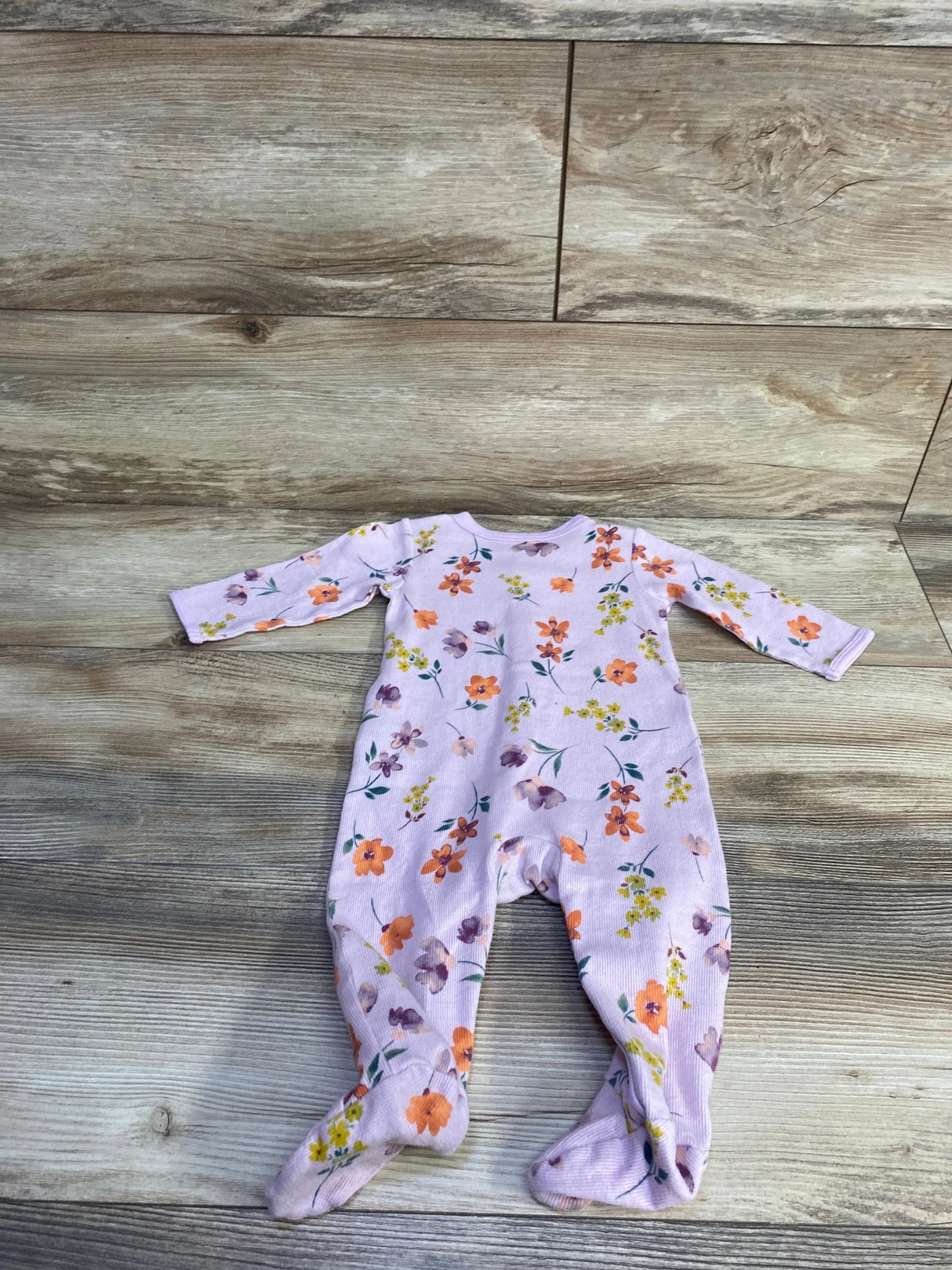 Top-down view of Carter's purple ribbed footed baby sleeper with orange and yellow floral print and long sleeves on wood background