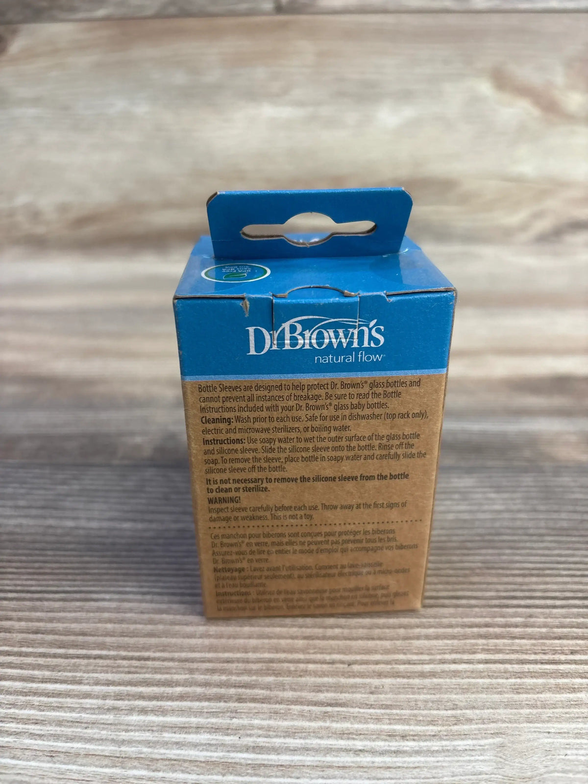 Front view of Dr. Brown's narrow silicone glass bottle sleeve box showing brand logo and text on a wood background