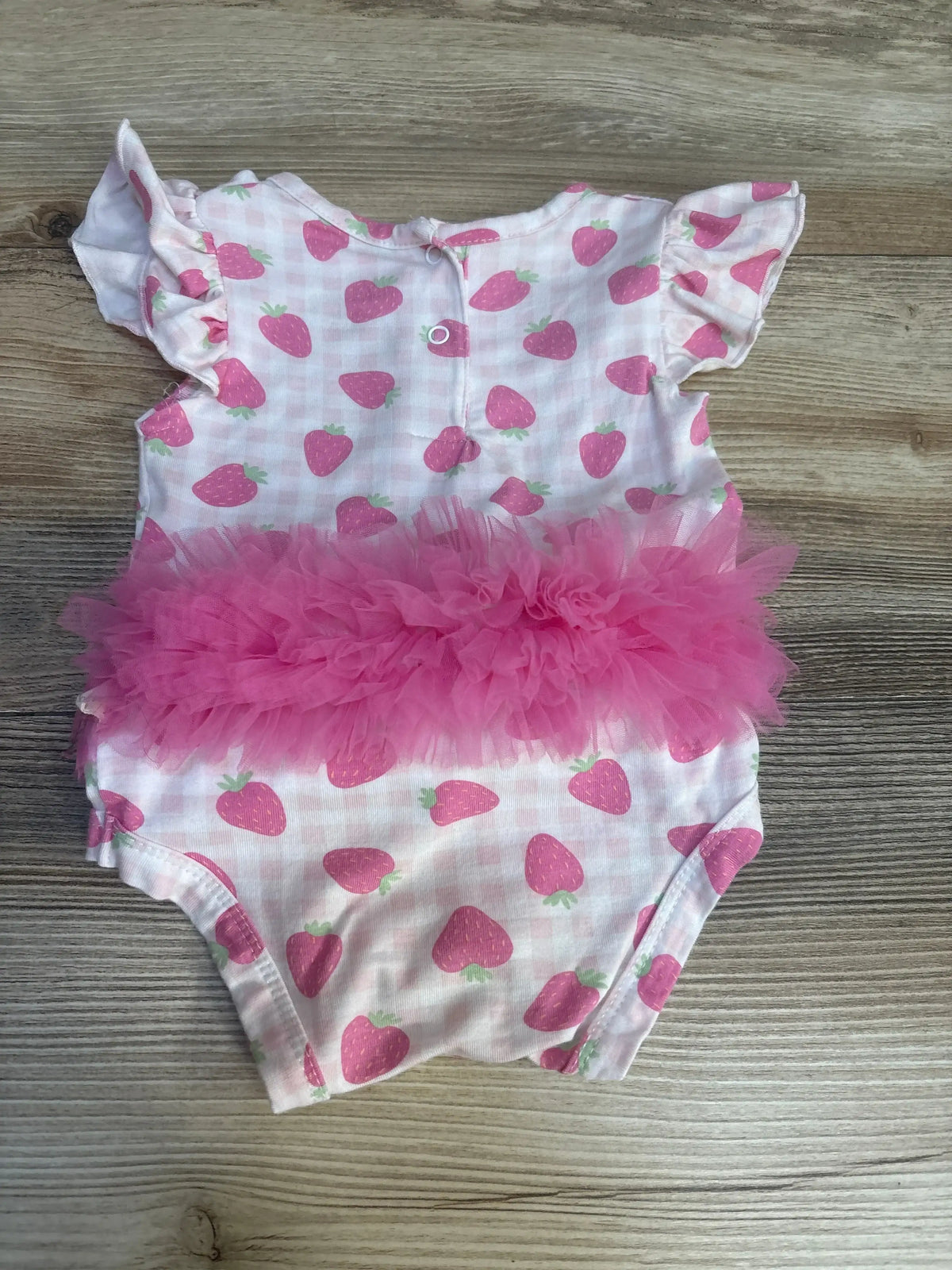 Pink strawberry print baby romper with ruffle tutu on wooden background