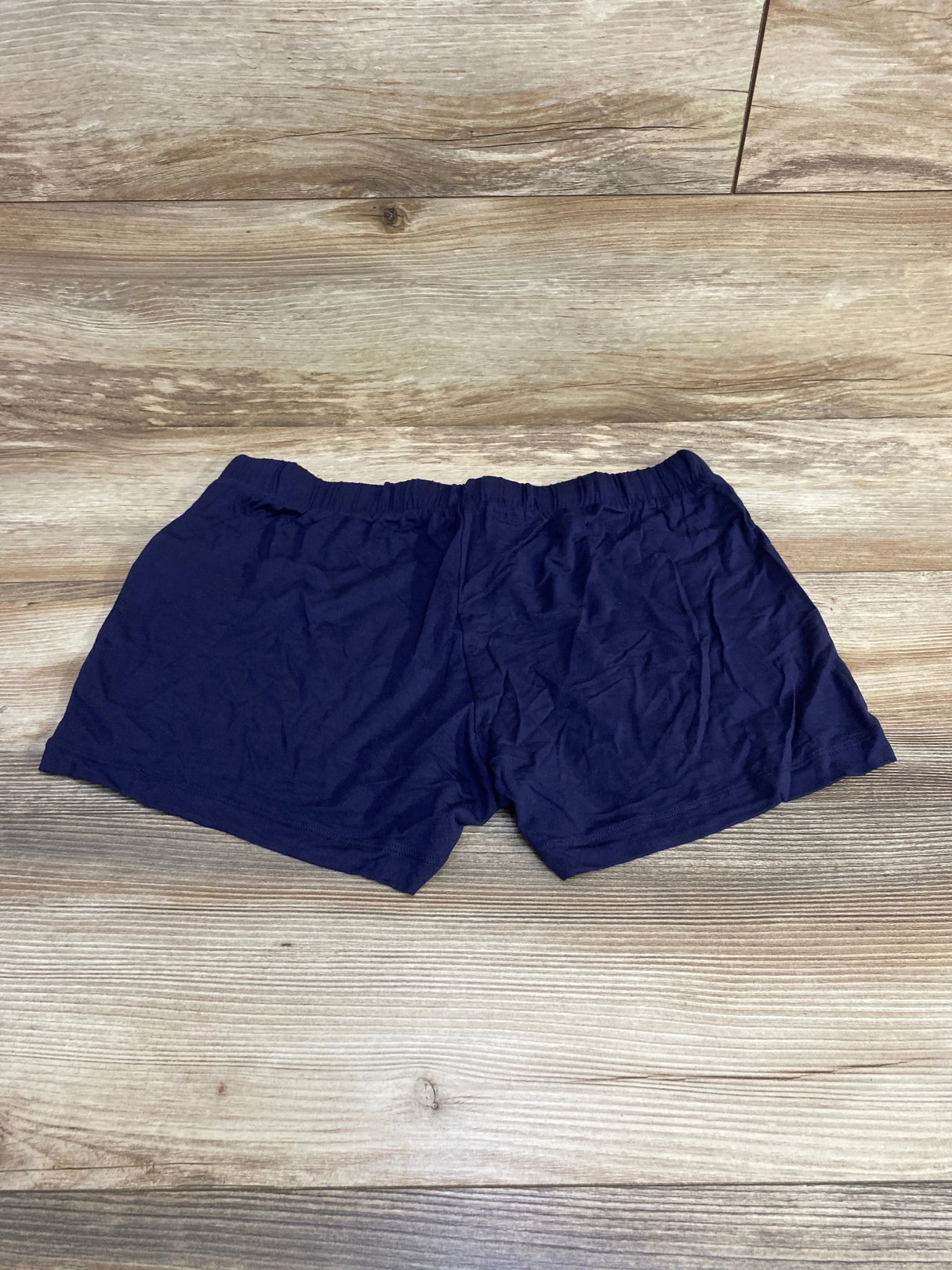Flat lay of Gap Body navy maternity modal shorts showcasing elastic maternity waistband and short inseam on wood floor background