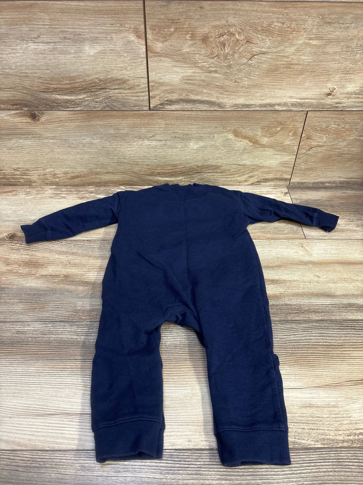 Flat lay of Carter’s Little Guy navy coverall showing long sleeves and ribbed ankle cuffs on wood background