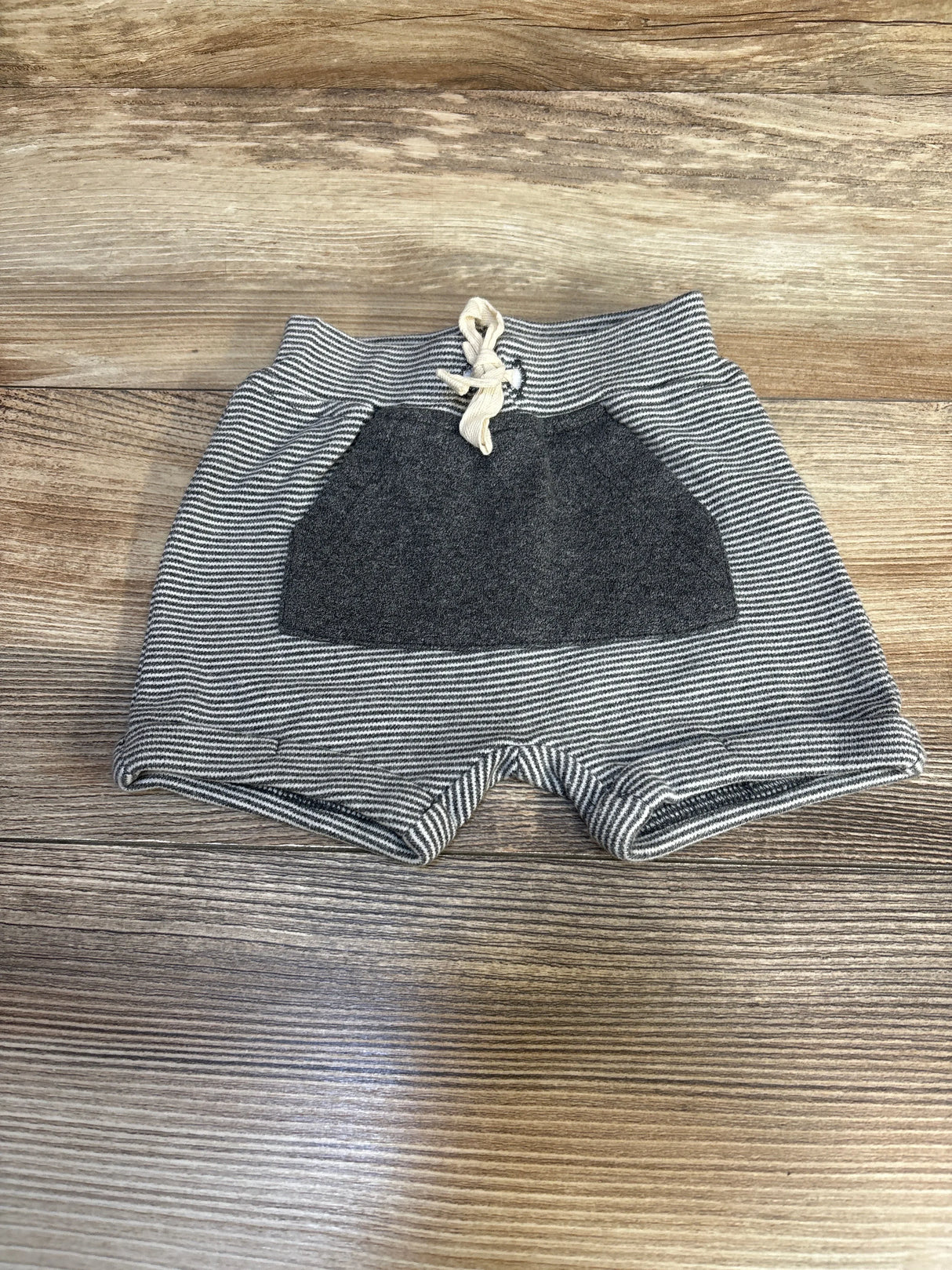Striped baby shorts with front pocket and drawstring on wood background