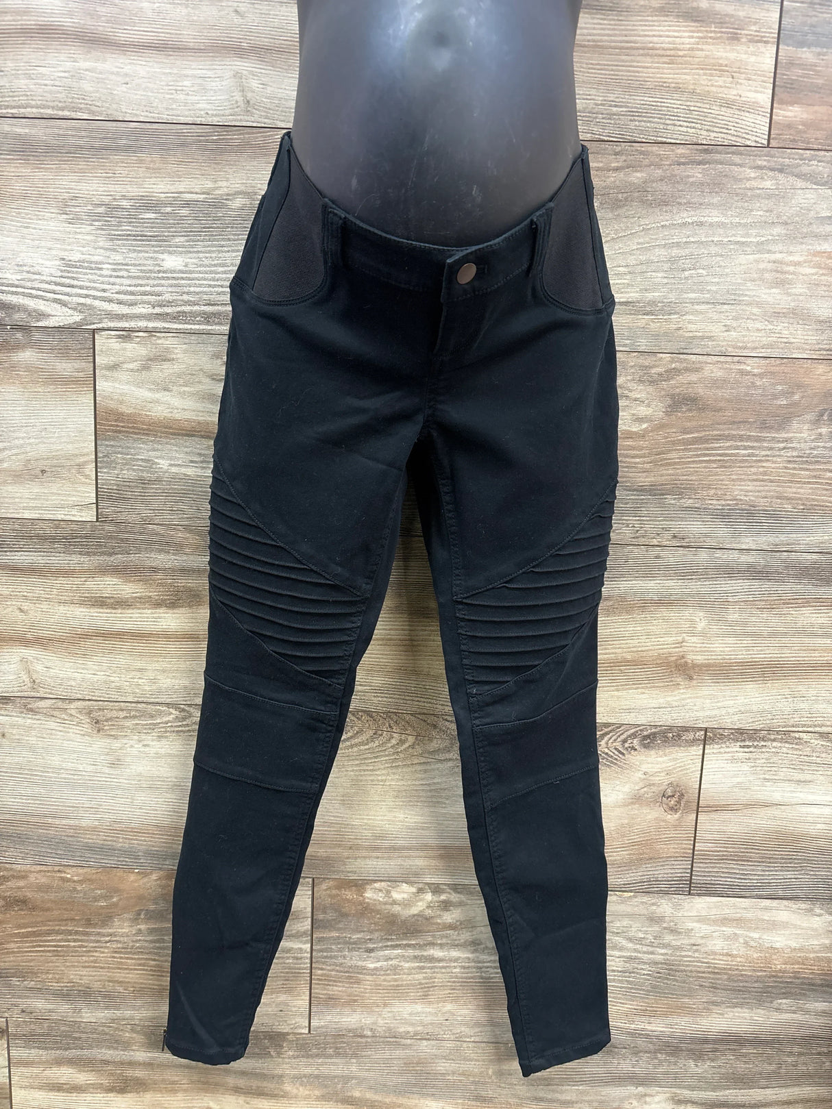 Black moto-style skinny jeans with ribbed knee detail on mannequin with wood floor background