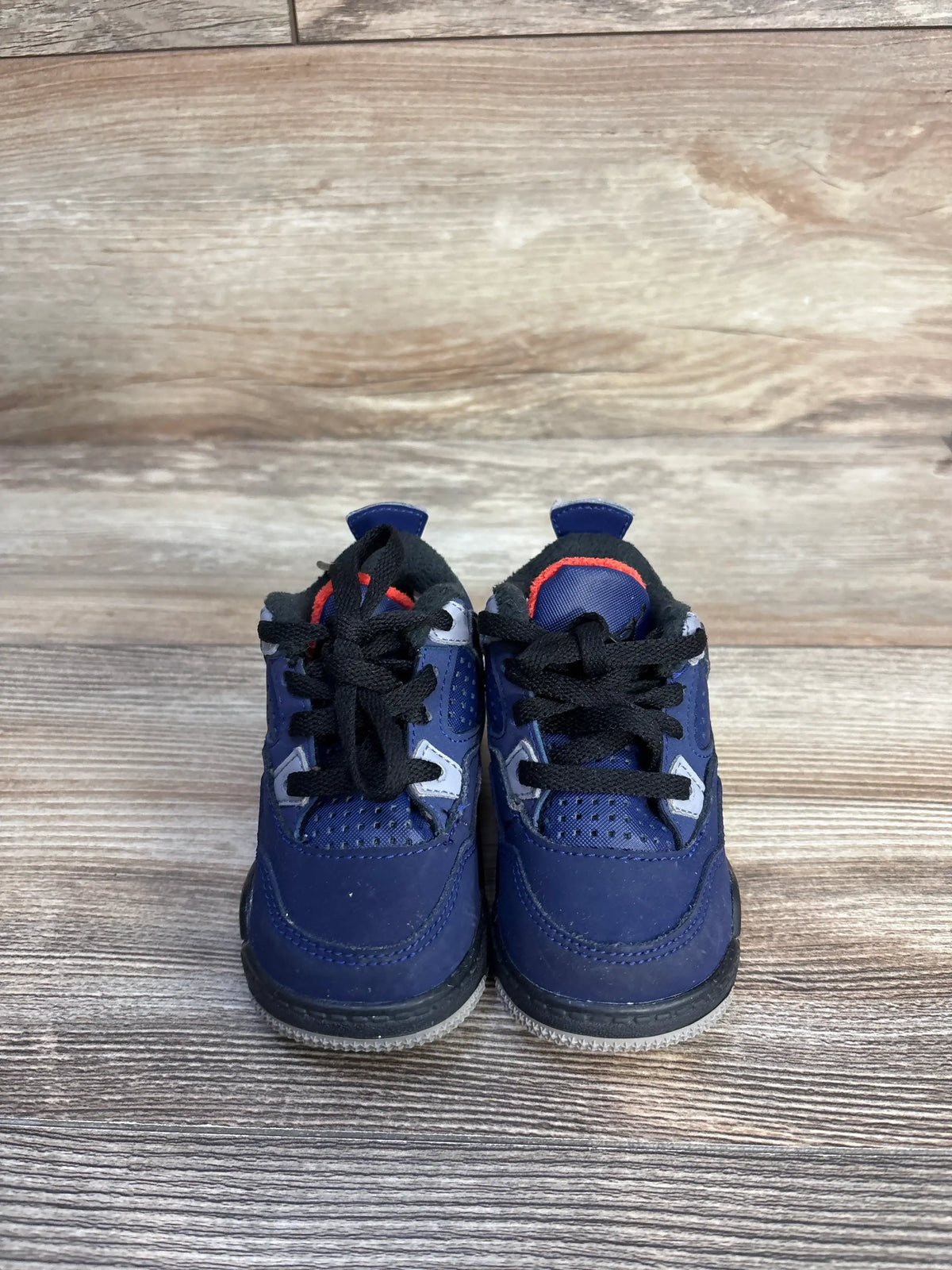 Front view of Air Jordan 4 Retro Winter TD toddler sneakers in Loyal Blue with black laces on a wood-grain surface