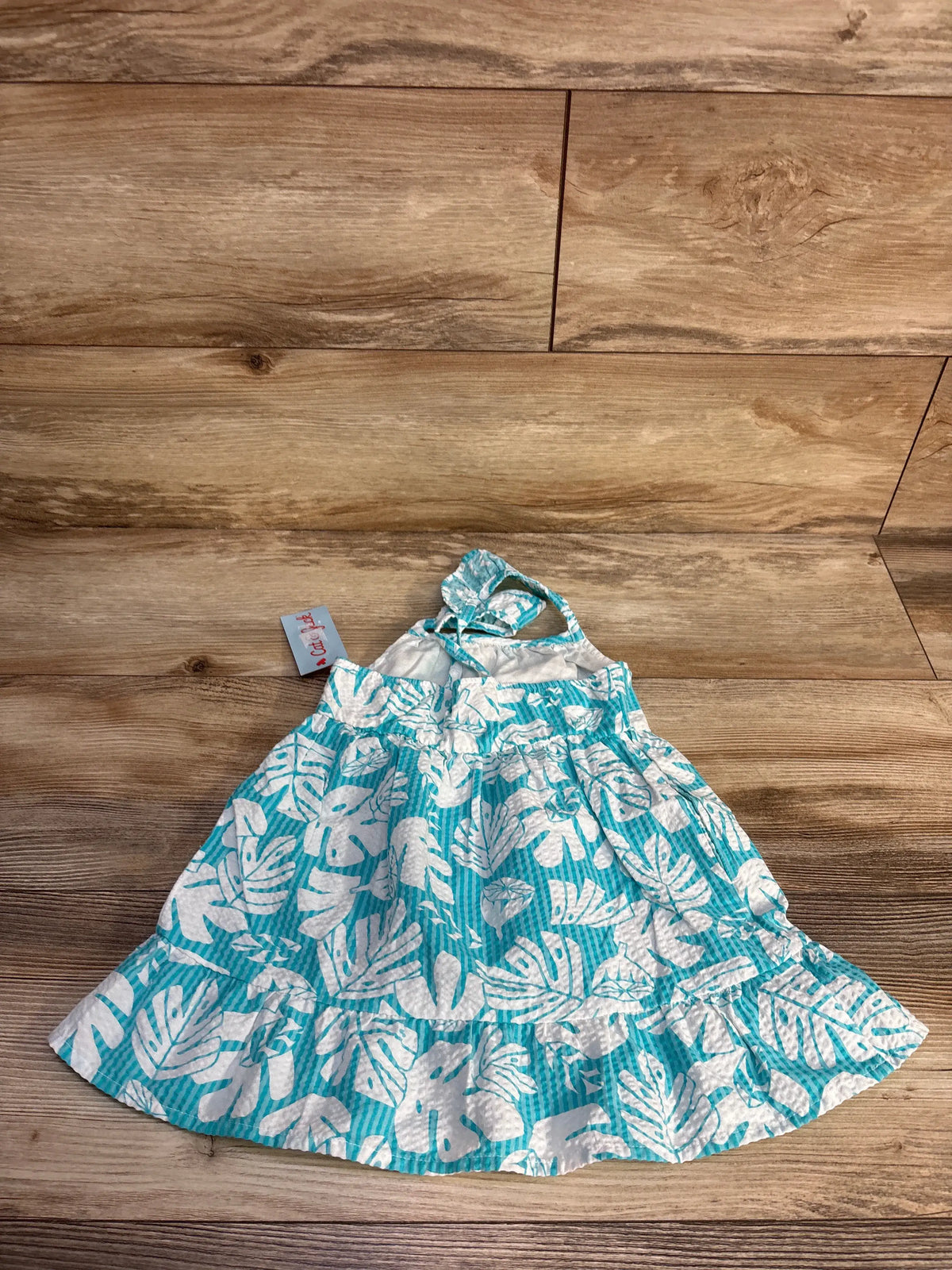 Front view of blue Cat & Jack palm print tank dress in size 2T showcasing sleeveless styling with a wood-look background