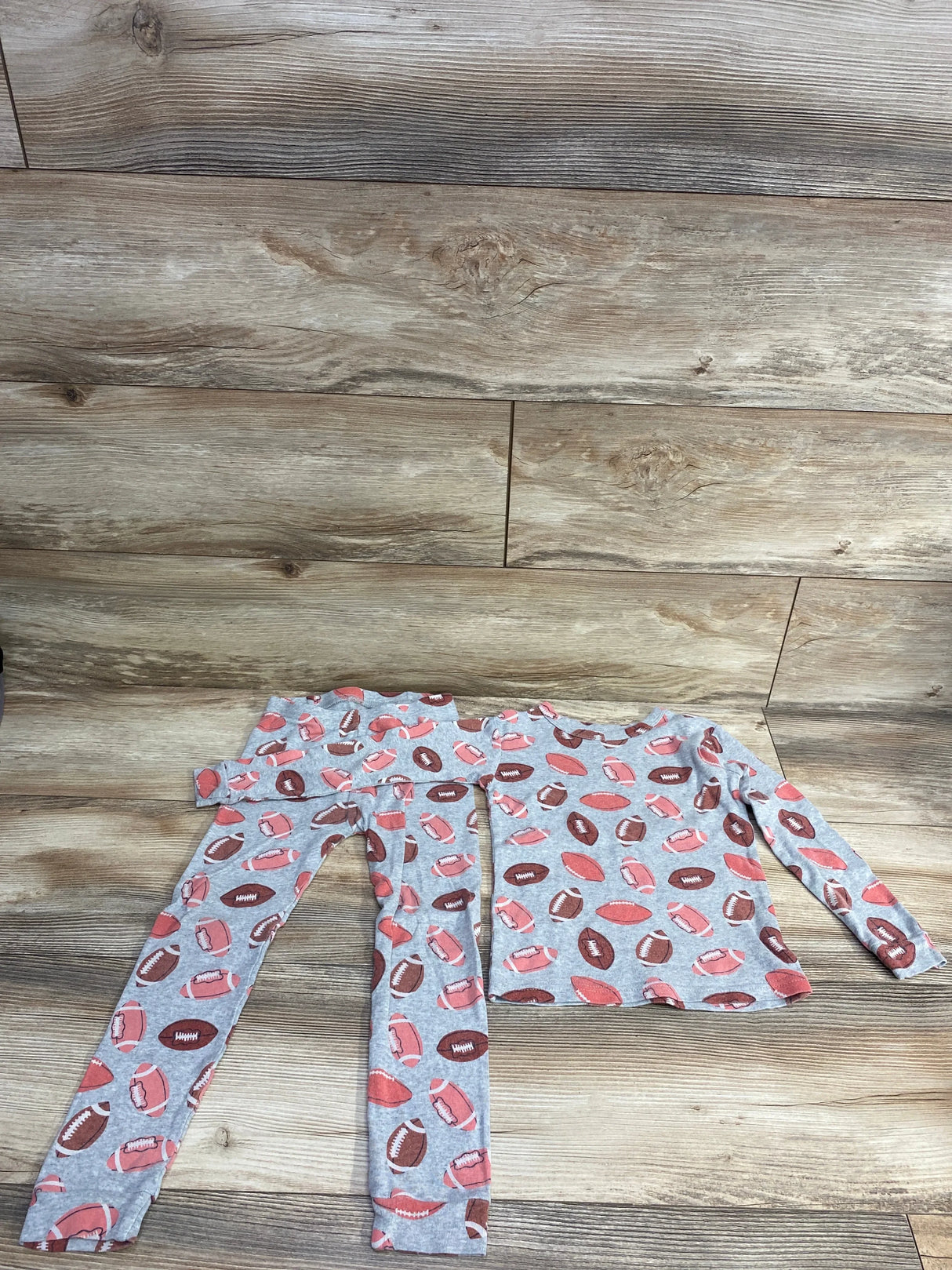 Flat lay of Baby Gap grey 2-piece toddler pajama set (5T) showing long-sleeve top and pants with football print
