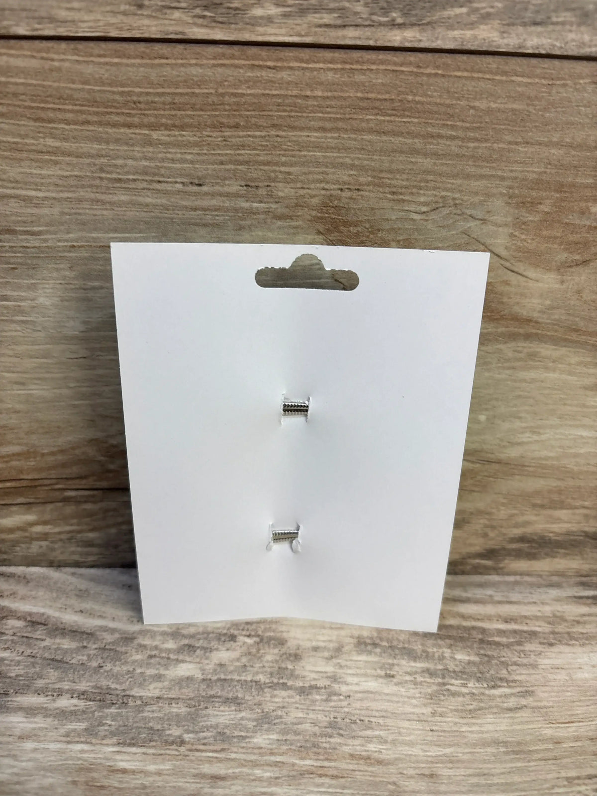 Back view of two light green hair bows showing their alligator clips on a white display card against a wood background