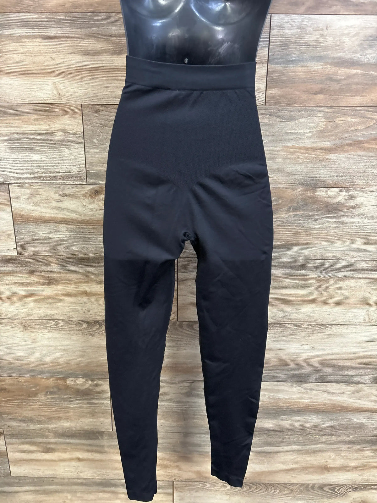 Front view of black belly-support maternity leggings showcasing a wide belly panel and full-length legs on a wood floor