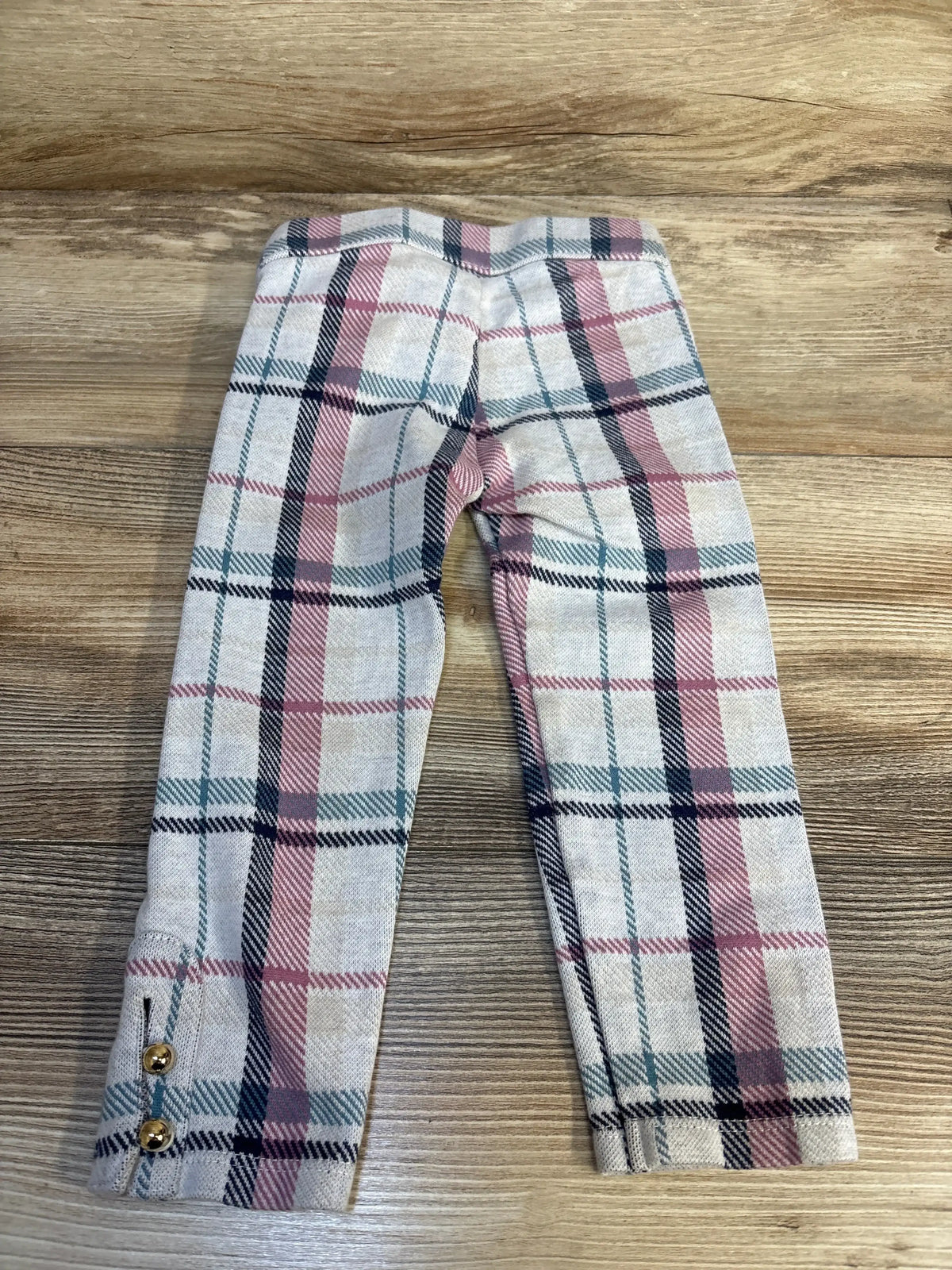 Pink and beige plaid toddler leggings with gold button accents, kids clothing flat lay