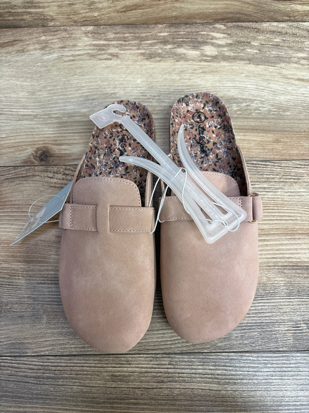 Pair of pink suede toddler slip-on shoes with floral insoles on wood background