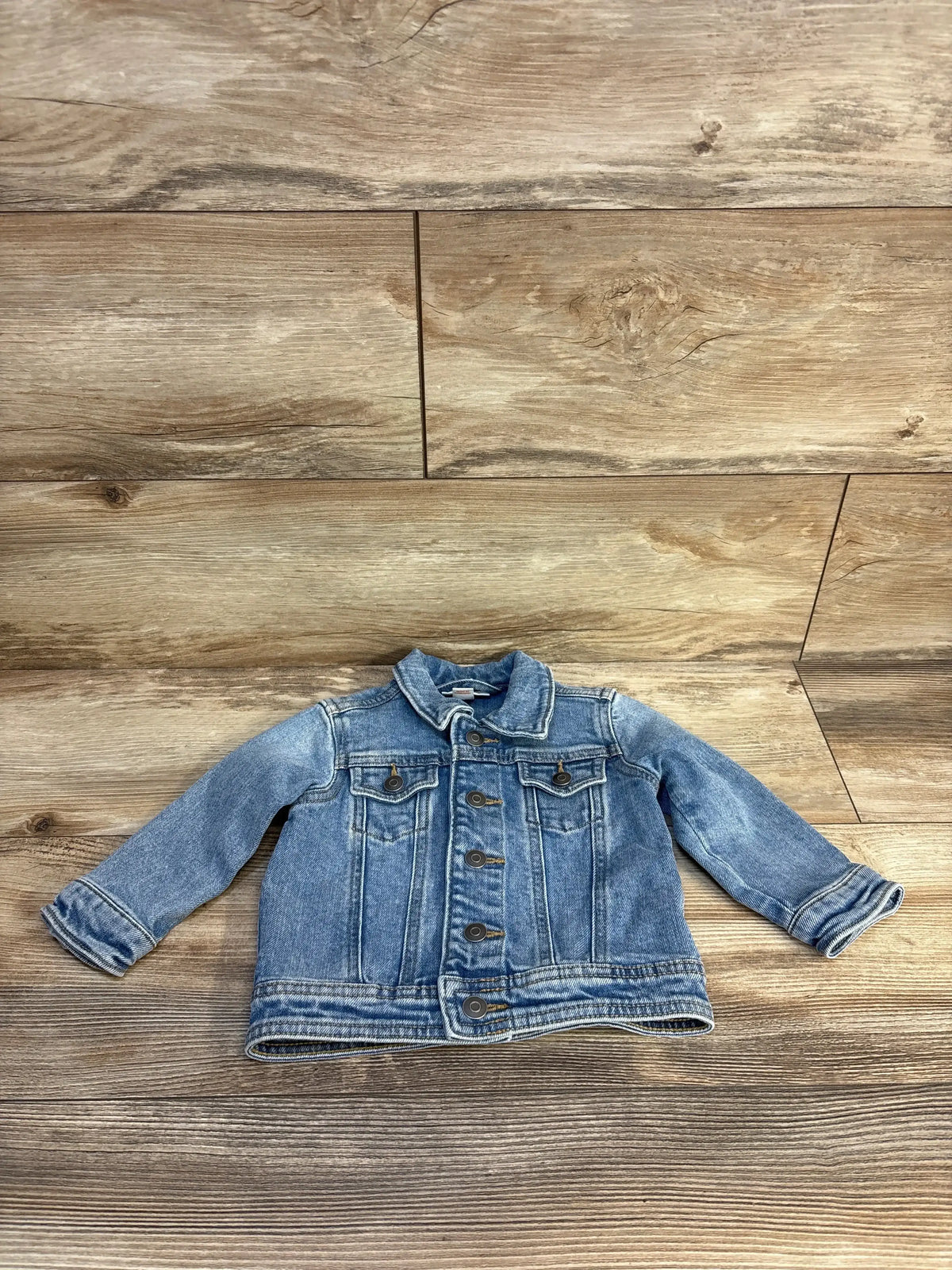 Gently used toddler denim jacket with button front on wood background