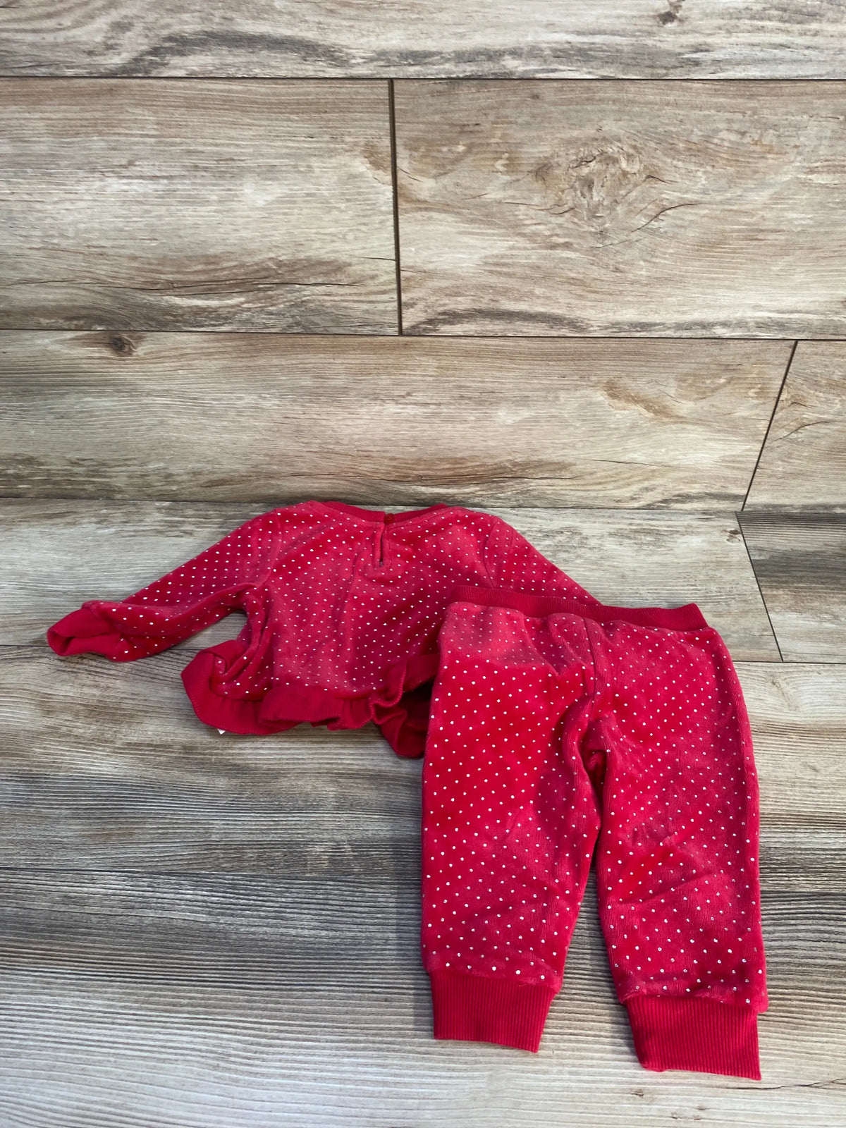 Overhead view of Juicy Couture red velvet peplum sweatshirt and joggers set showcasing white dot pattern on wood flooring