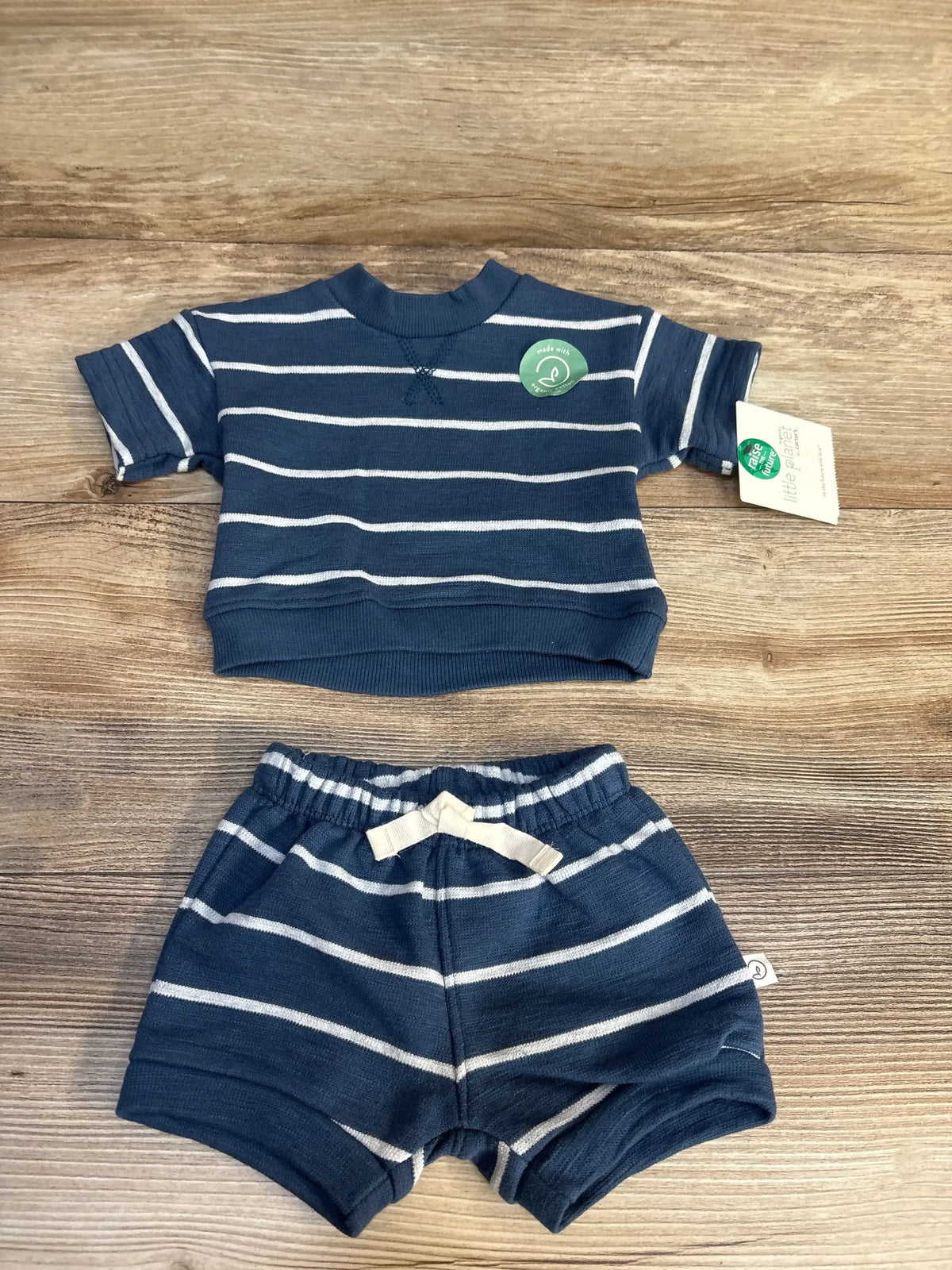 Navy and white striped baby outfit with organic cotton tag, laid on wood floor