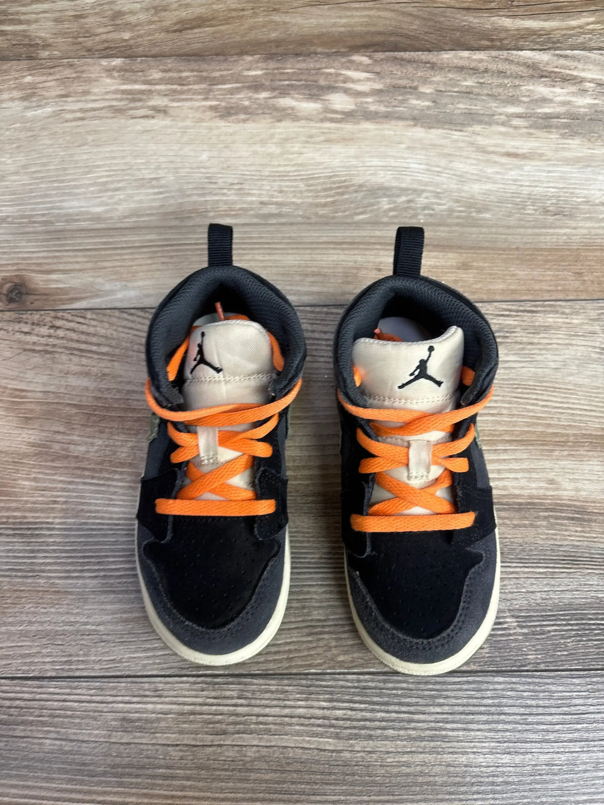 Top-down view of Air Jordan 1 Mid SE Craft toddler sneakers, anthracite, showing orange laces and Jumpman logo on wood floor