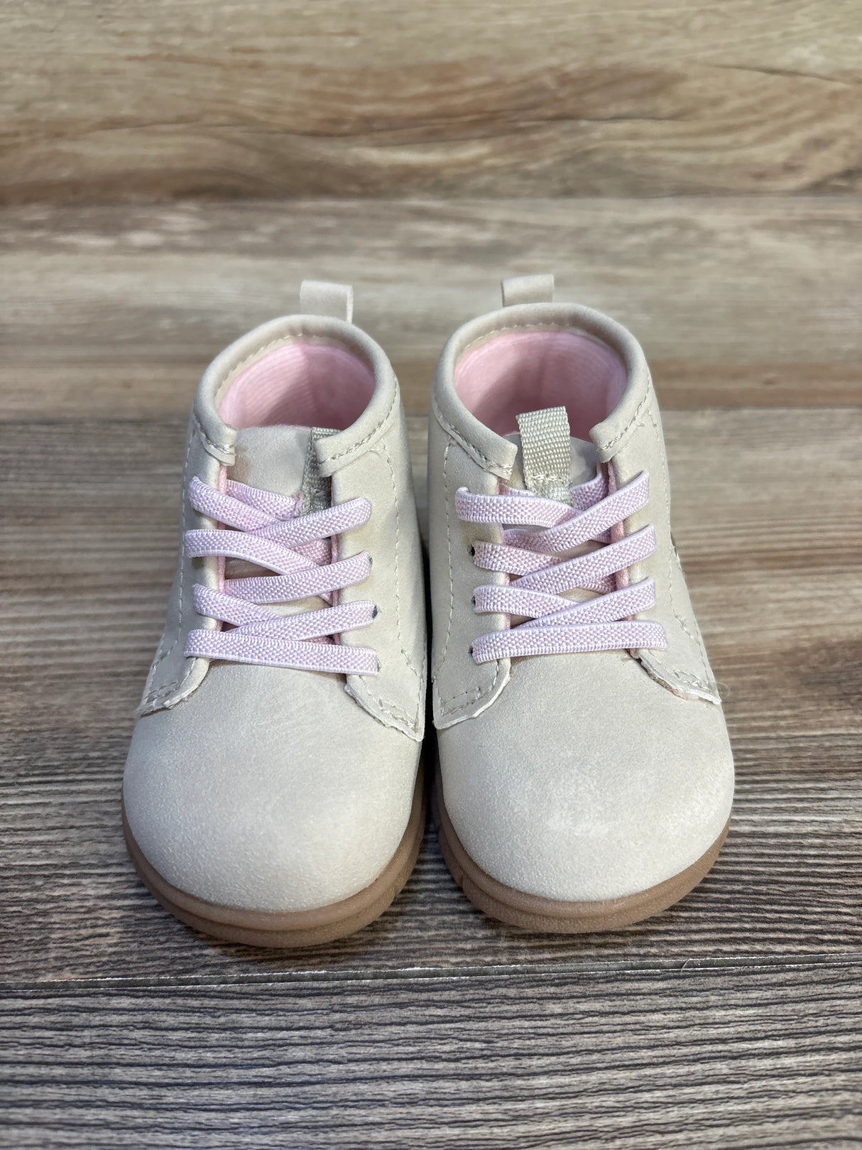 Front view of Just One You Cressida first walker boots, 4C, tan upper with pink lining and laces, brown soles on wood