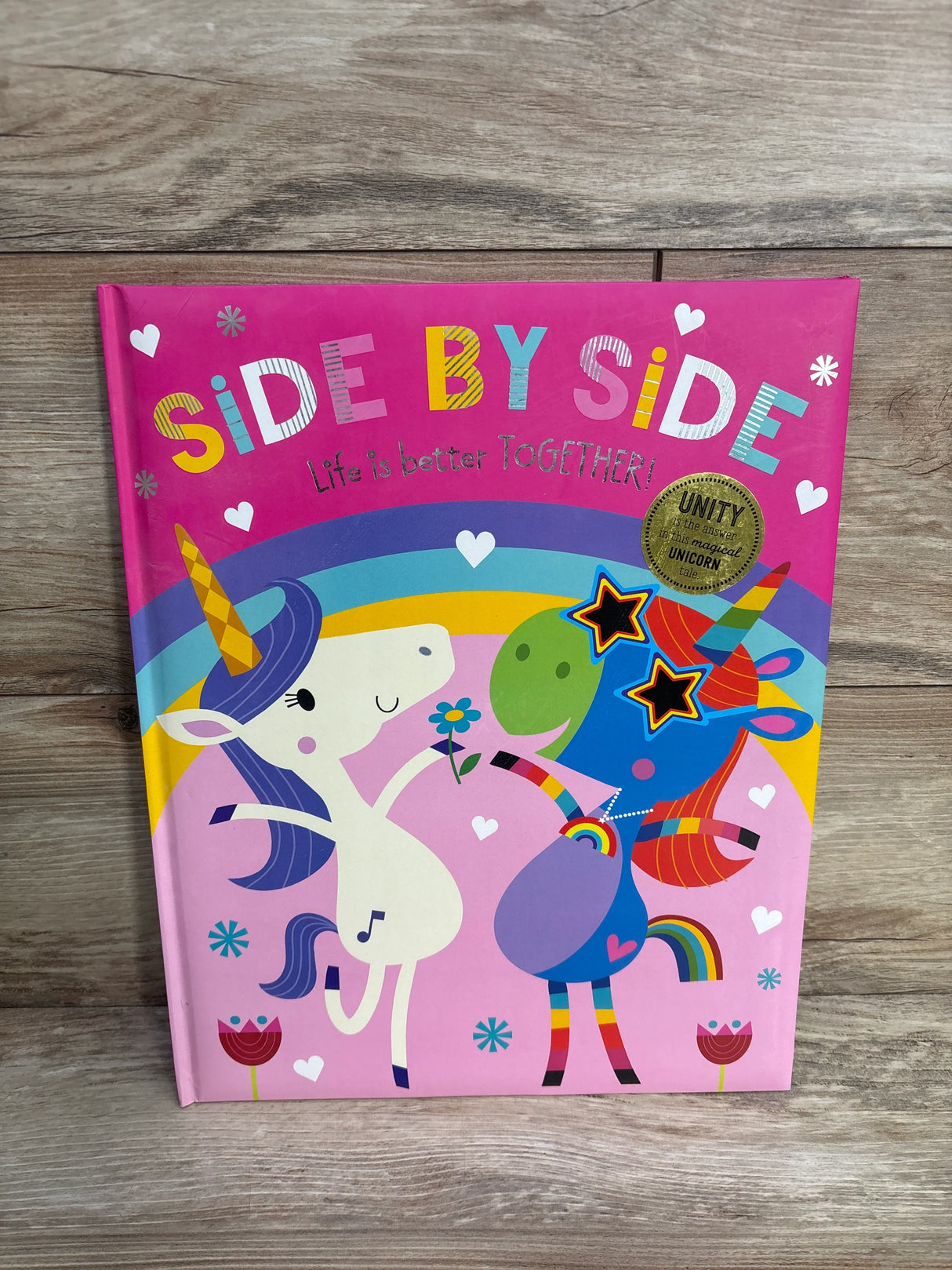 Children's book cover 'Side by Side' with colorful unicorns, rainbow, and hearts on pink background