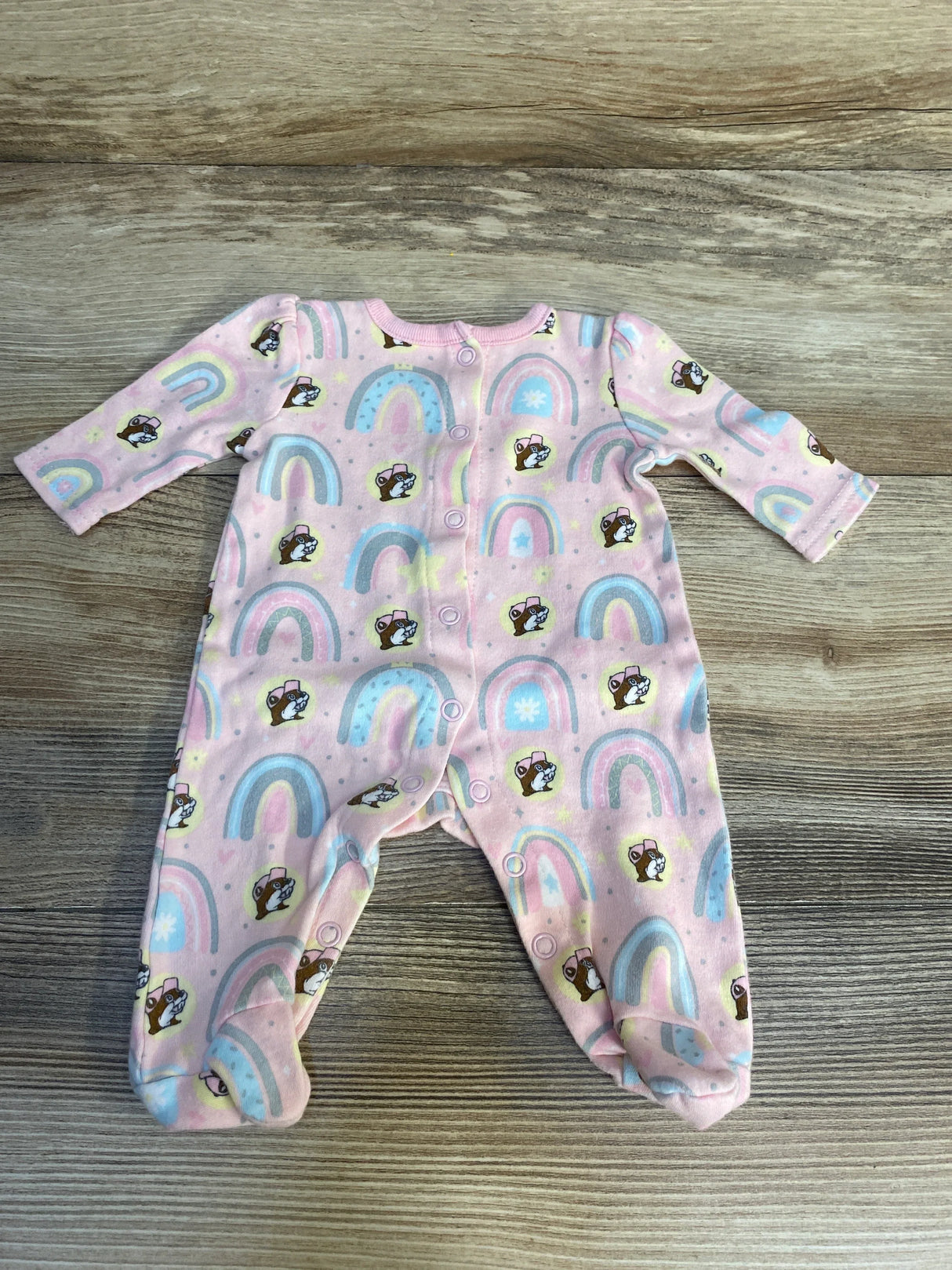 Pink baby sleeper with rainbow and puppy print, long sleeves, snap closure, laid flat on wood