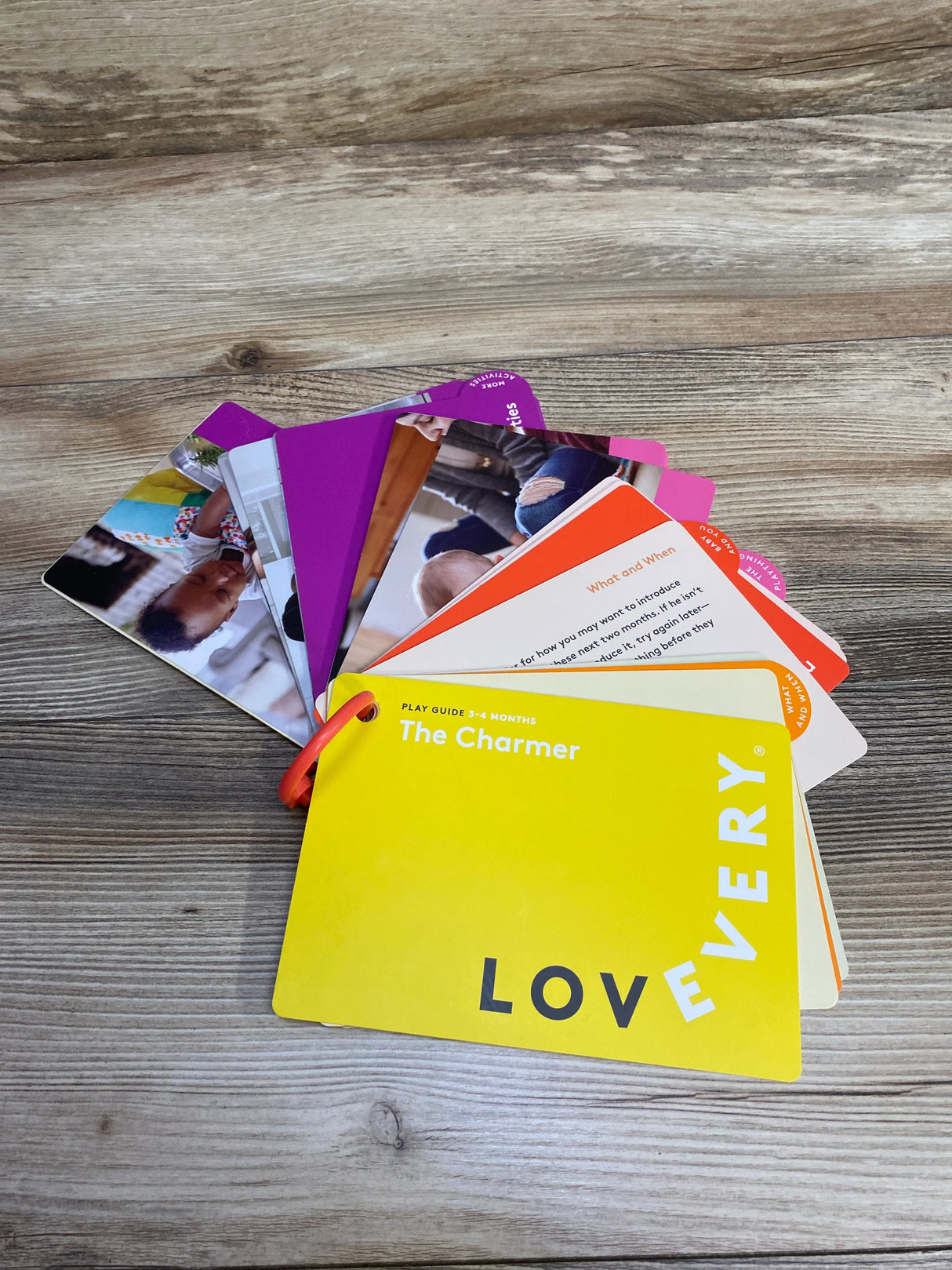 Lovevery The Charmer play guide cards for 3-4 months on wooden surface