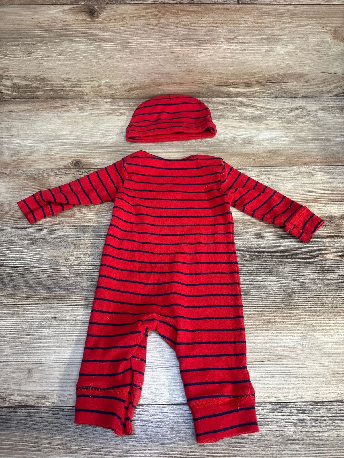 Red and navy striped baby romper with matching hat on wood background