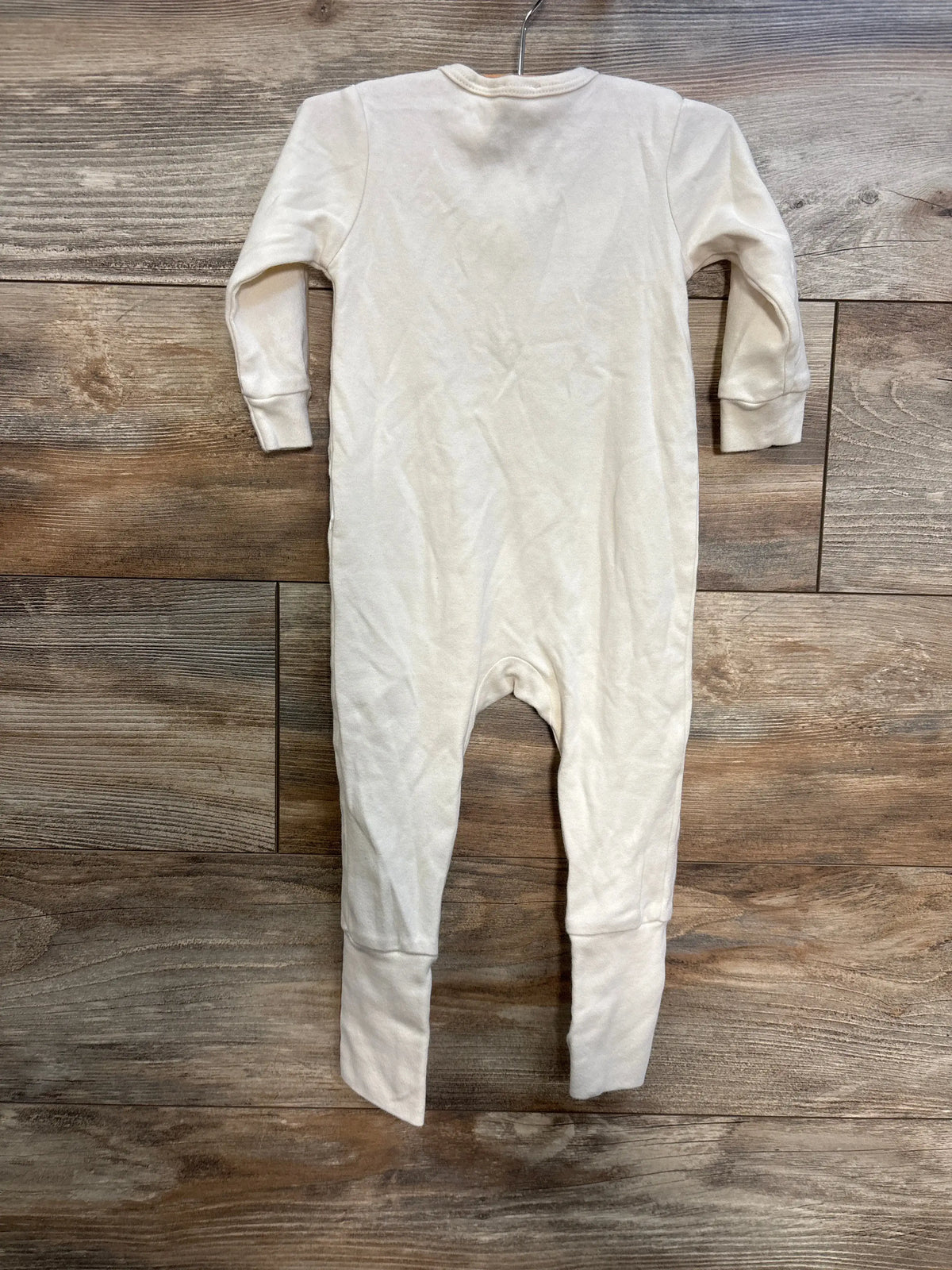 Front view of Jamie Kay cream convertible sleeper for 6-12 months, with long sleeves, on a wood floor