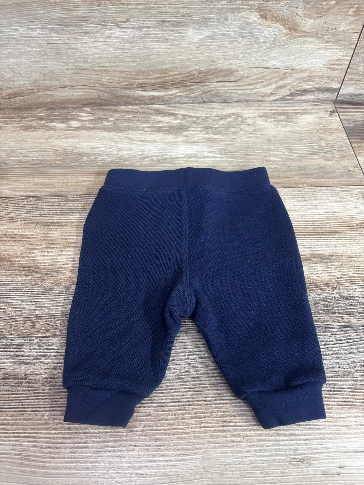 Flat lay of navy Ralph Lauren baby joggers (3 months) showing ribbed cuffs and elastic waistband on wood background