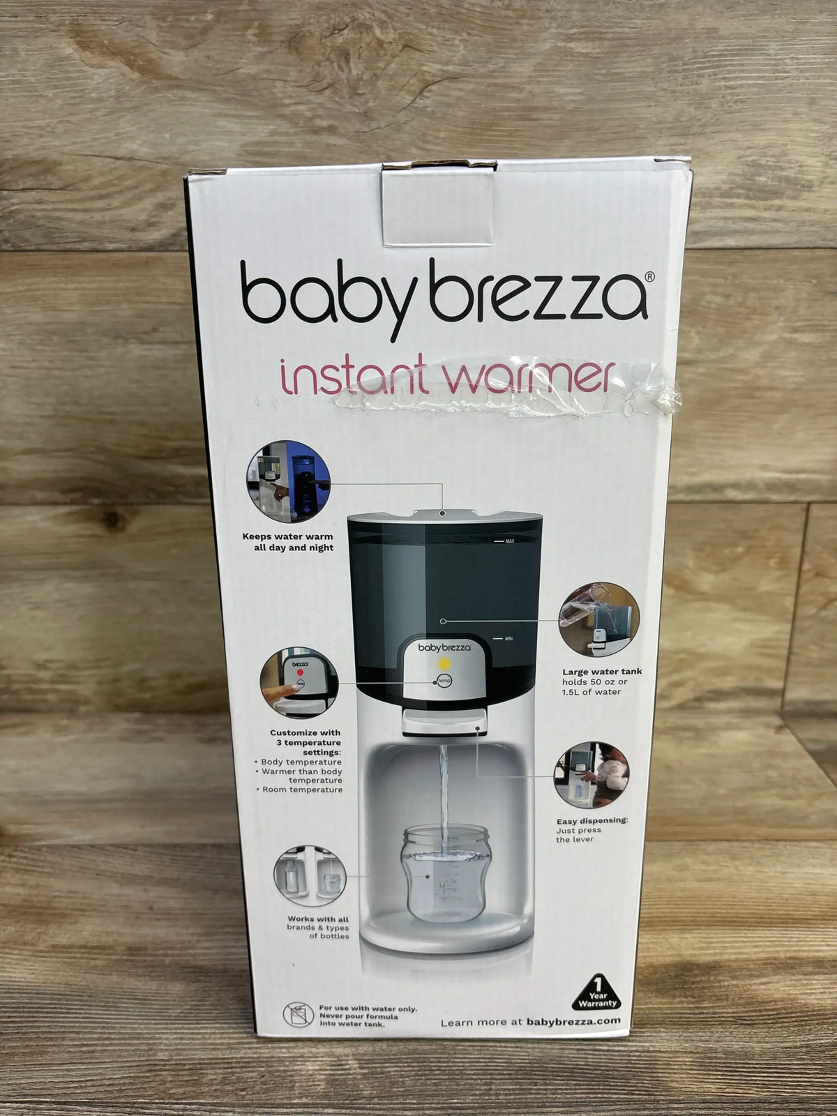 Front view of Baby Brezza Instant Bottle Warmer box showing product image and feature callouts on a wooden tabletop background