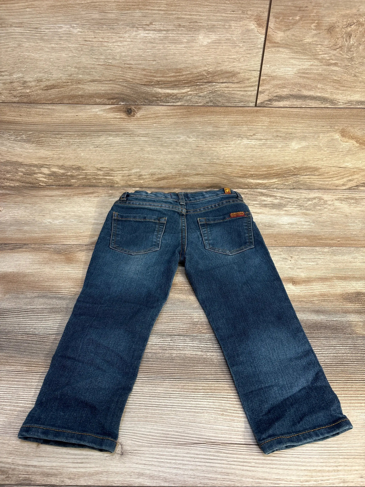 Back view of toddler blue 7 For All Mankind jeans size 2T showing elastic waistband and back pockets on wood floor