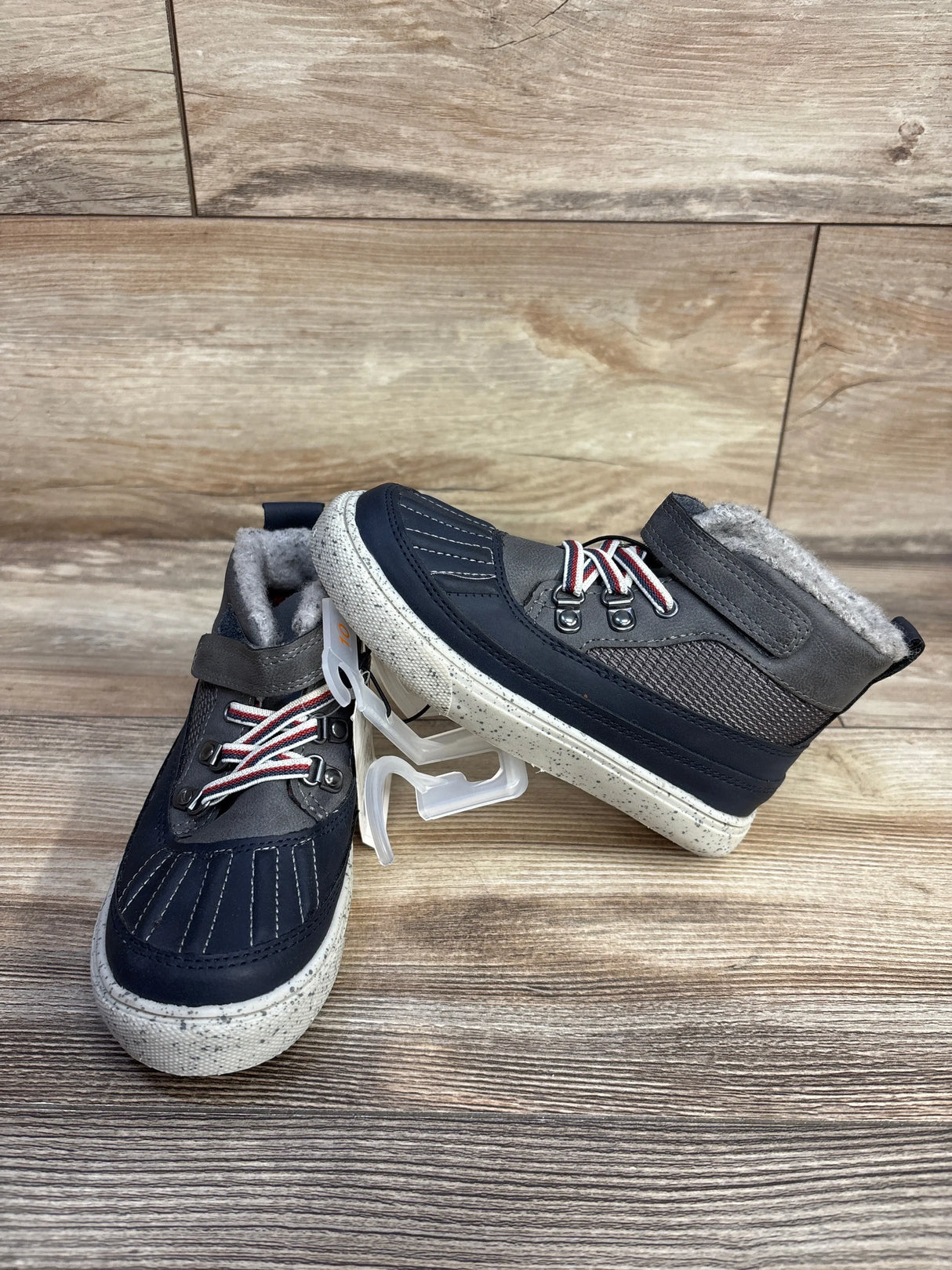 Gray and navy toddler winter boots with fleece lining and white speckled soles on wood surface