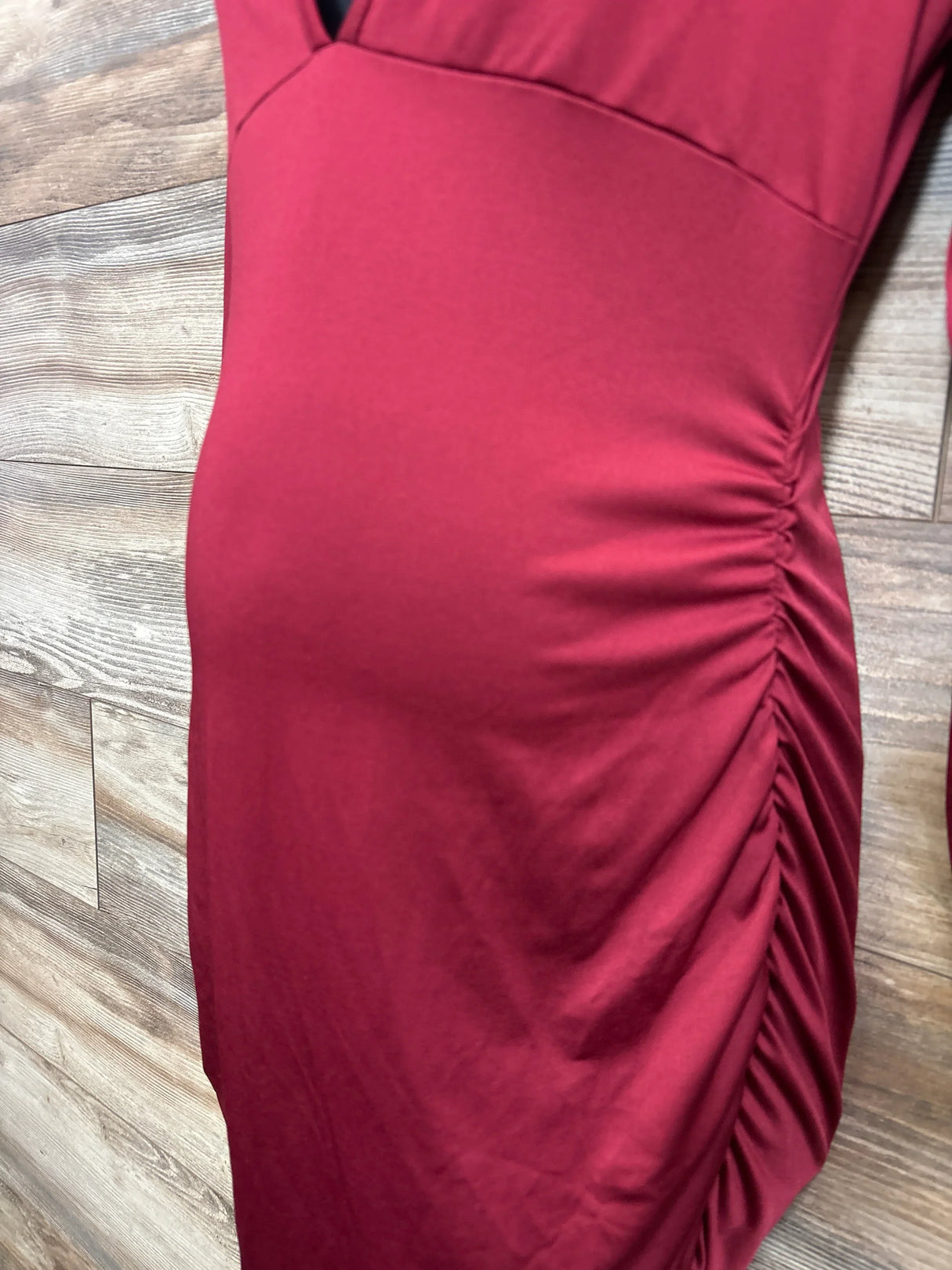 Red ruched maternity dress close-up against wood background