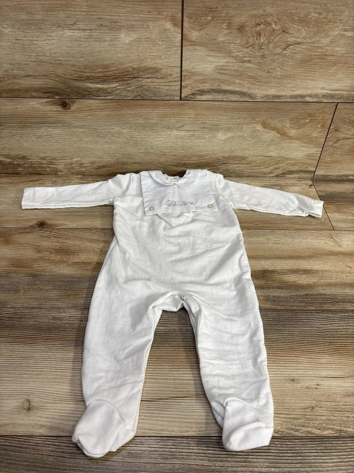 White long sleeve baby footed romper with embroidered animal design on wood background