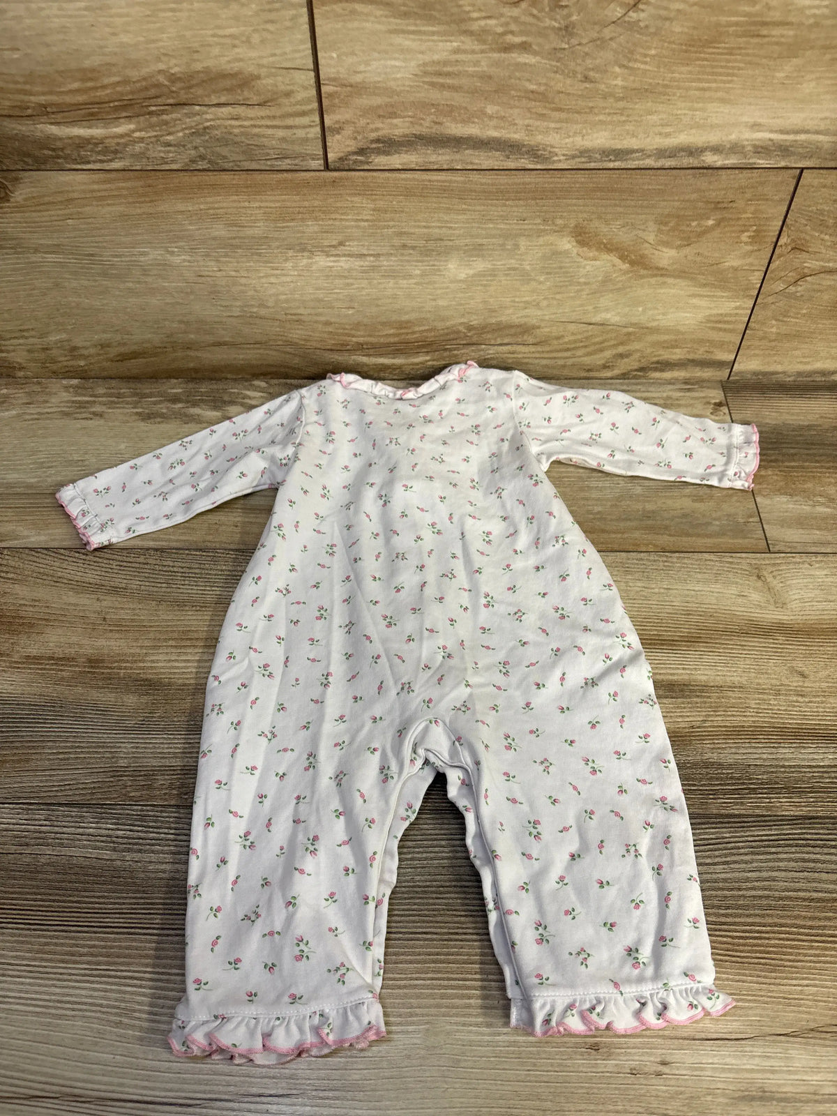 Front view of Kissy Kissy floral ruffle sleeper in white showcasing floral print and ruffled cuffs on a wood surface