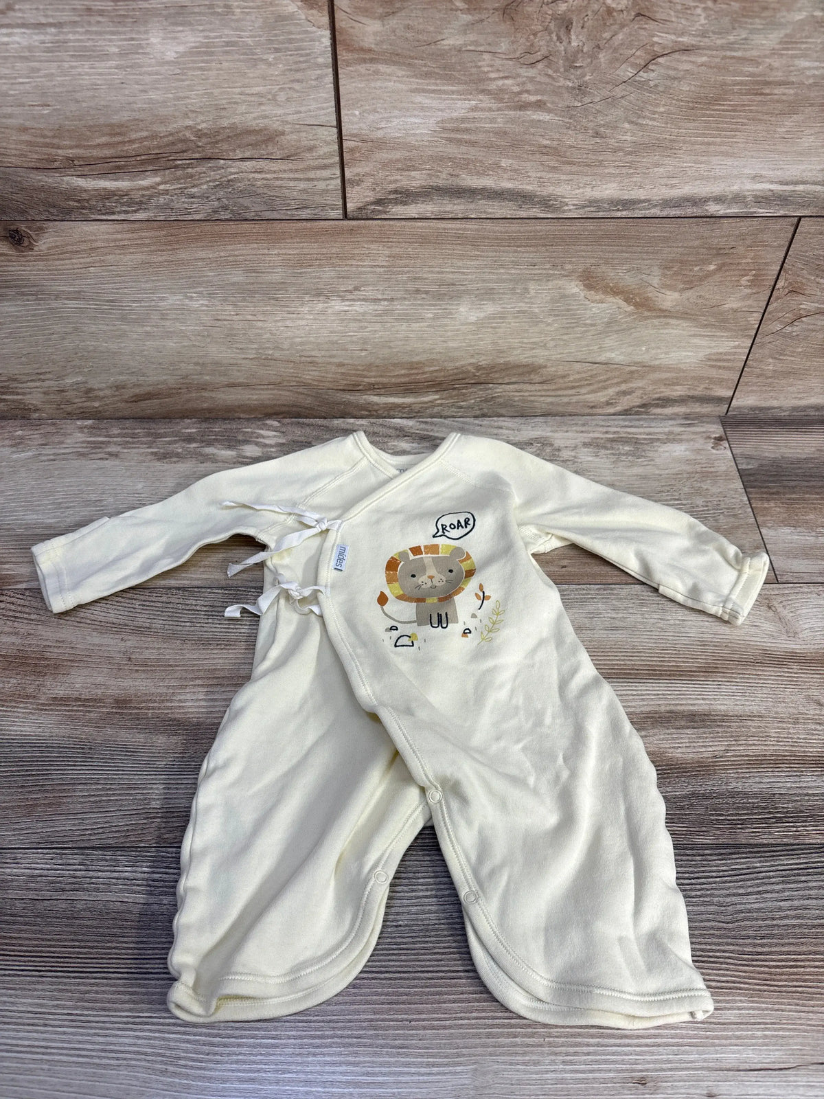 Flat-lay of Mides yellow kimono romper (size 3 months) showing lion graphic, kimono-style snap front and long sleeves on wood floor
