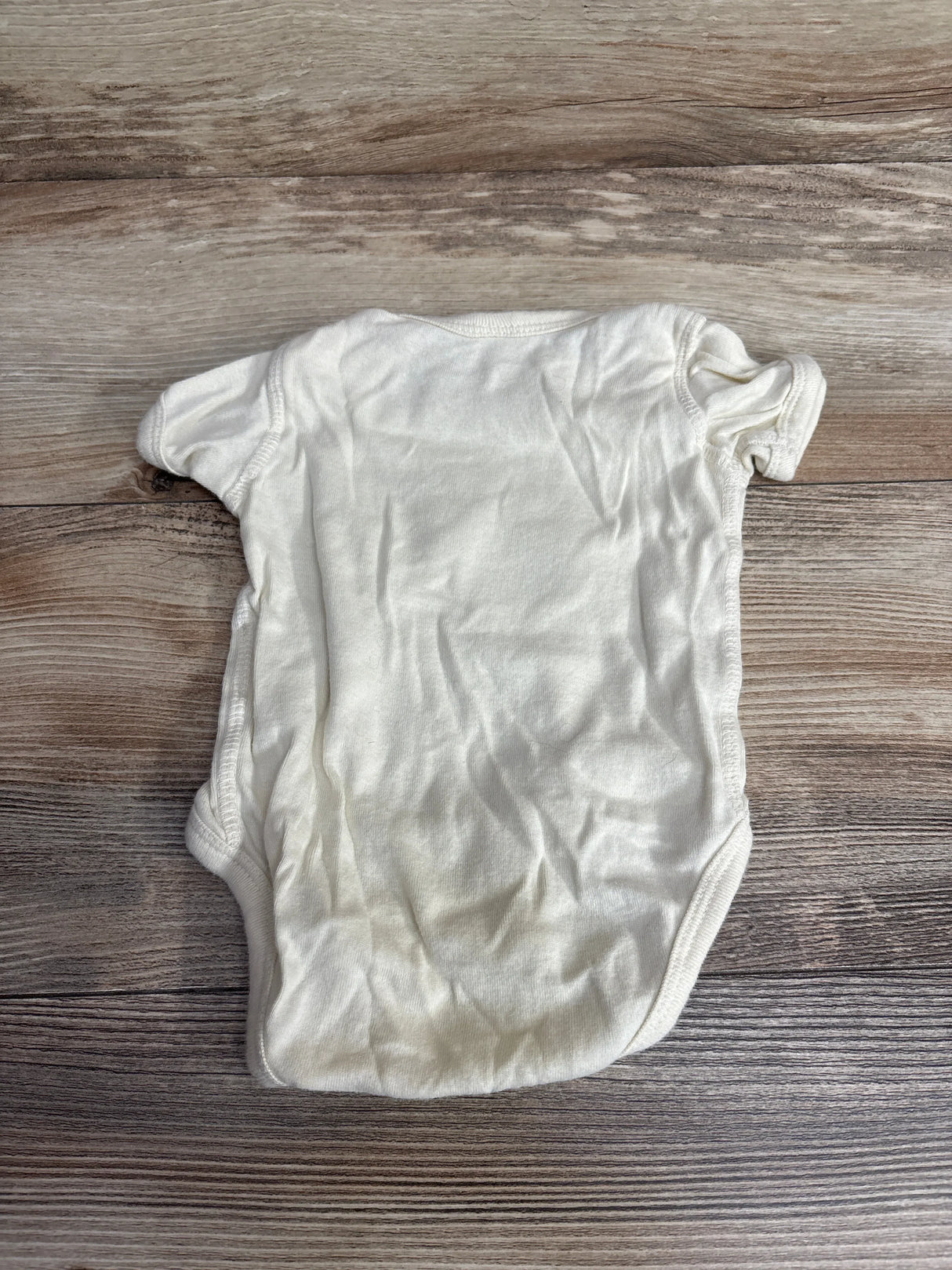 Back view of Rabbit Skins World Changer cream baby bodysuit in 6M showing its plain 100% cotton back on a wooden background