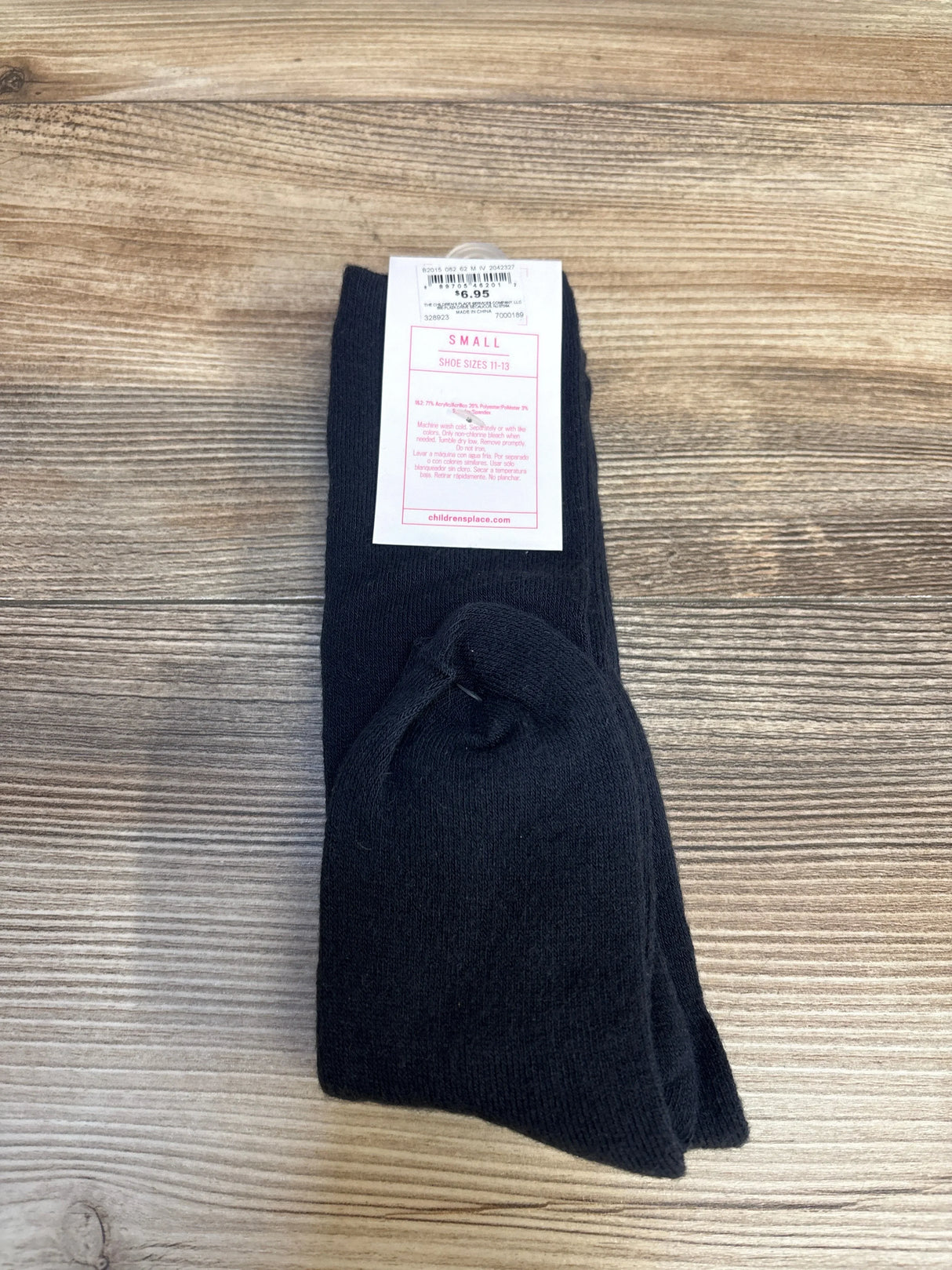 Pair of small black children's socks with tag, displayed on wood surface