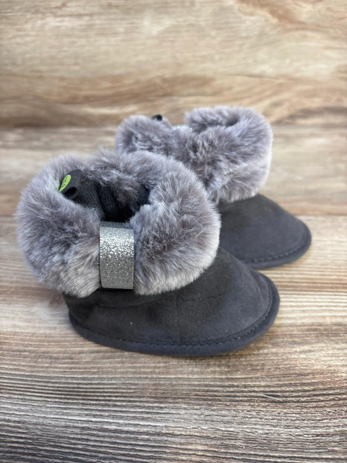 Gray faux fur lined baby booties with silver strap on wood background