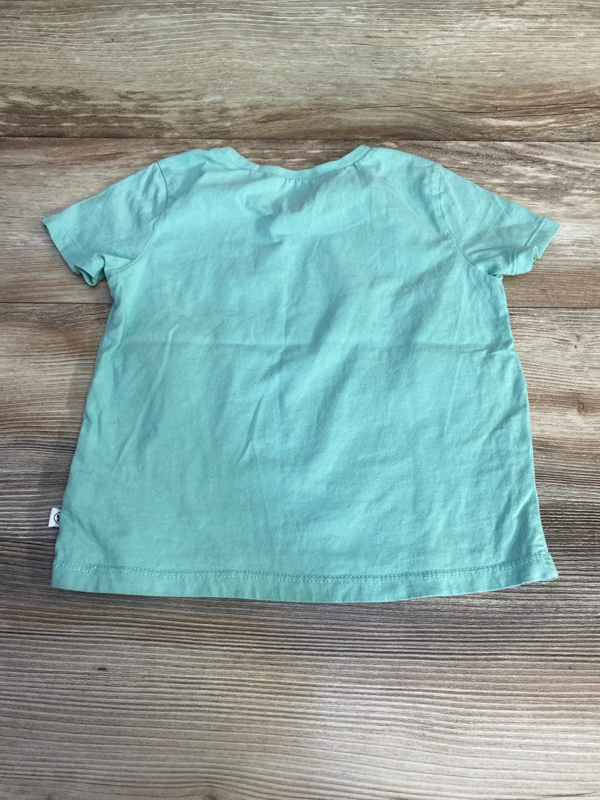 Back view of Honest Baby To Infinity and Beyond shirt in solid mint green showcasing short sleeves and crew neck on wood plank floor