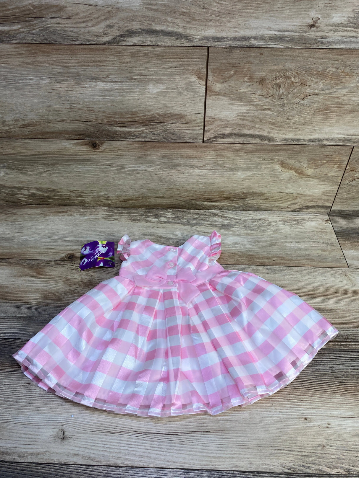 Top-down view of Blueberi Boulevard pink gingham dress size 6-9 months showing bow, flutter sleeves, buttons on wood background
