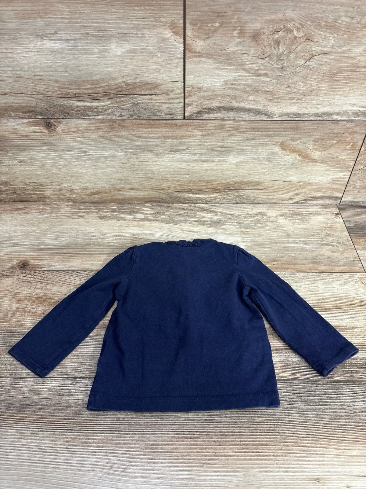Navy blue long sleeve toddler shirt on wood floor background