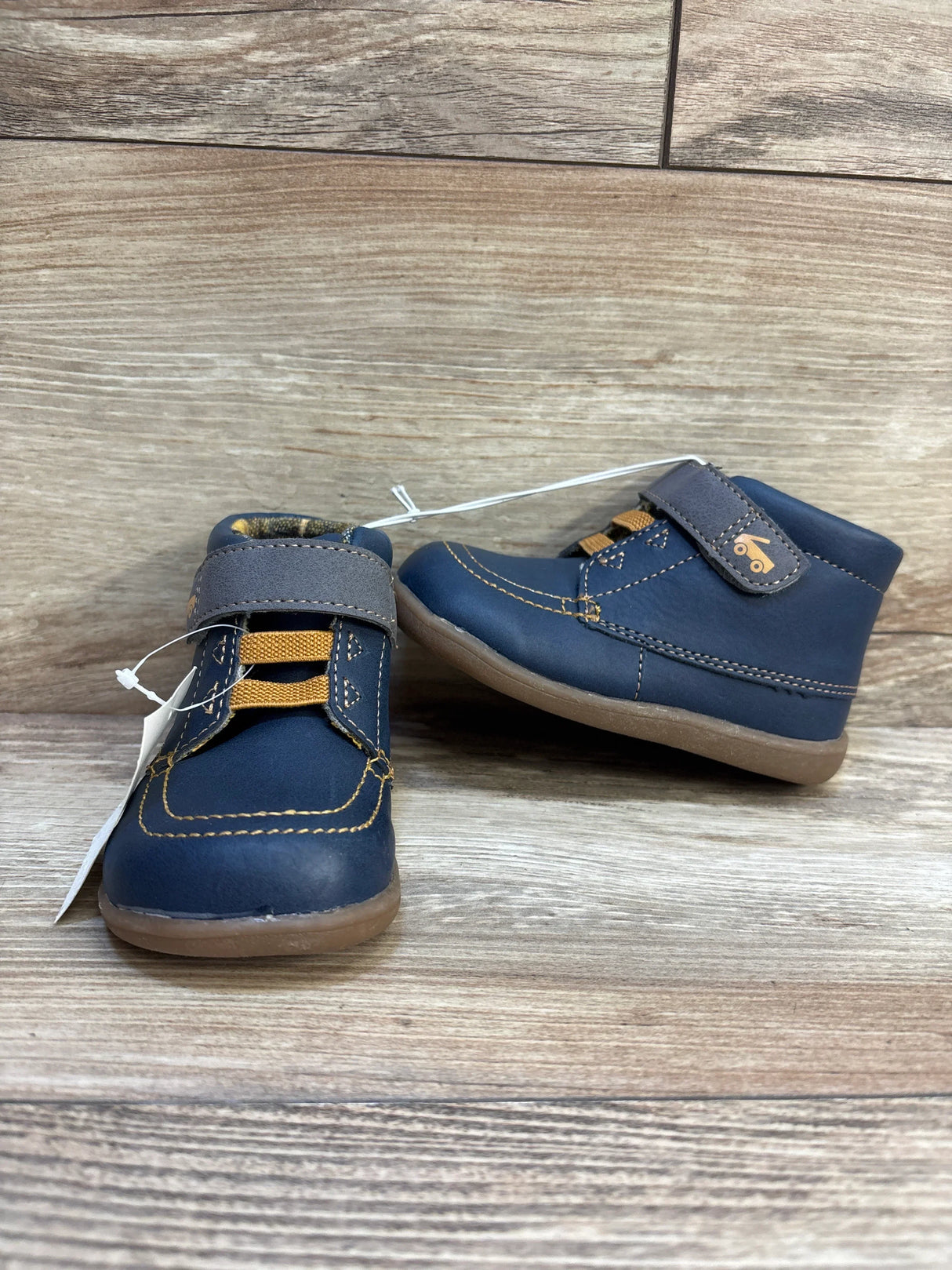 Blue toddler shoes with yellow accents and velcro straps on wooden background