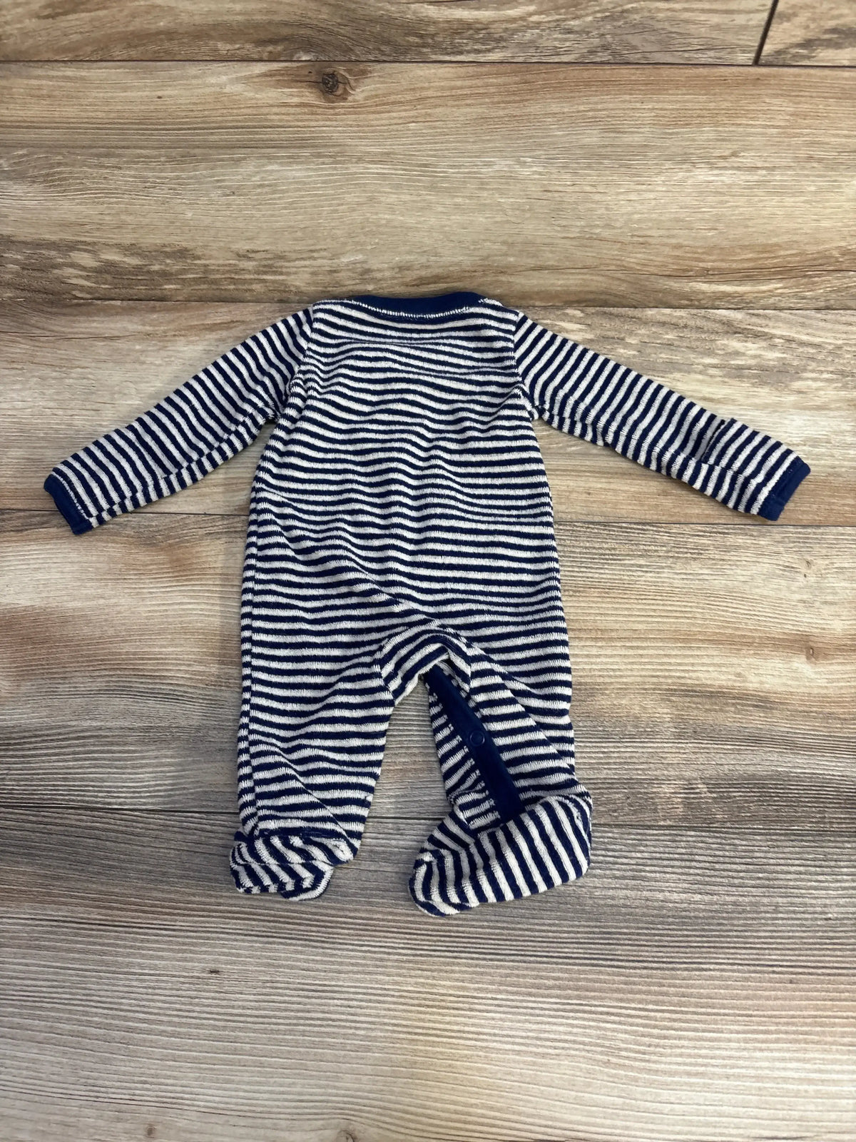 Flat lay of Carters navy and white striped terry cloth footed sleeper with front zipper on wood plank background