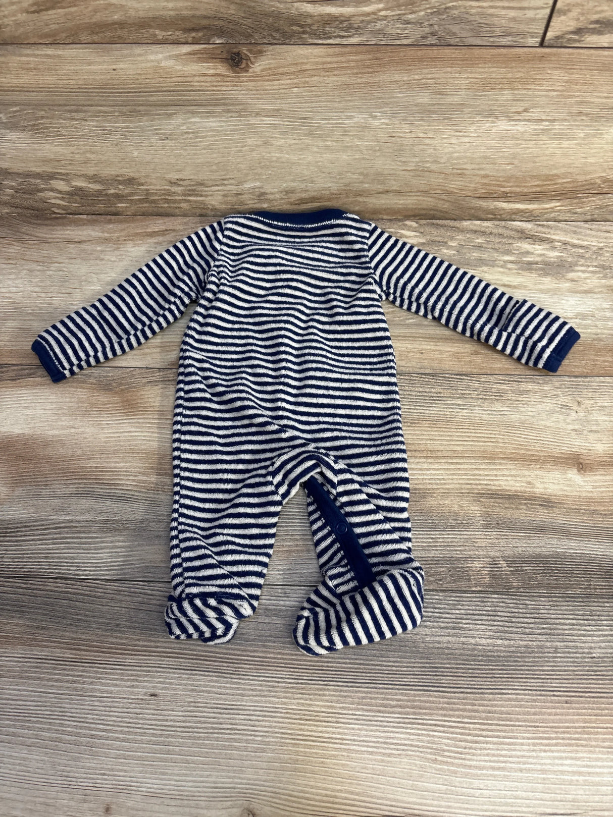 Back view of newborn navy-and-white striped terry footed sleeper with snap inseam on light wood background